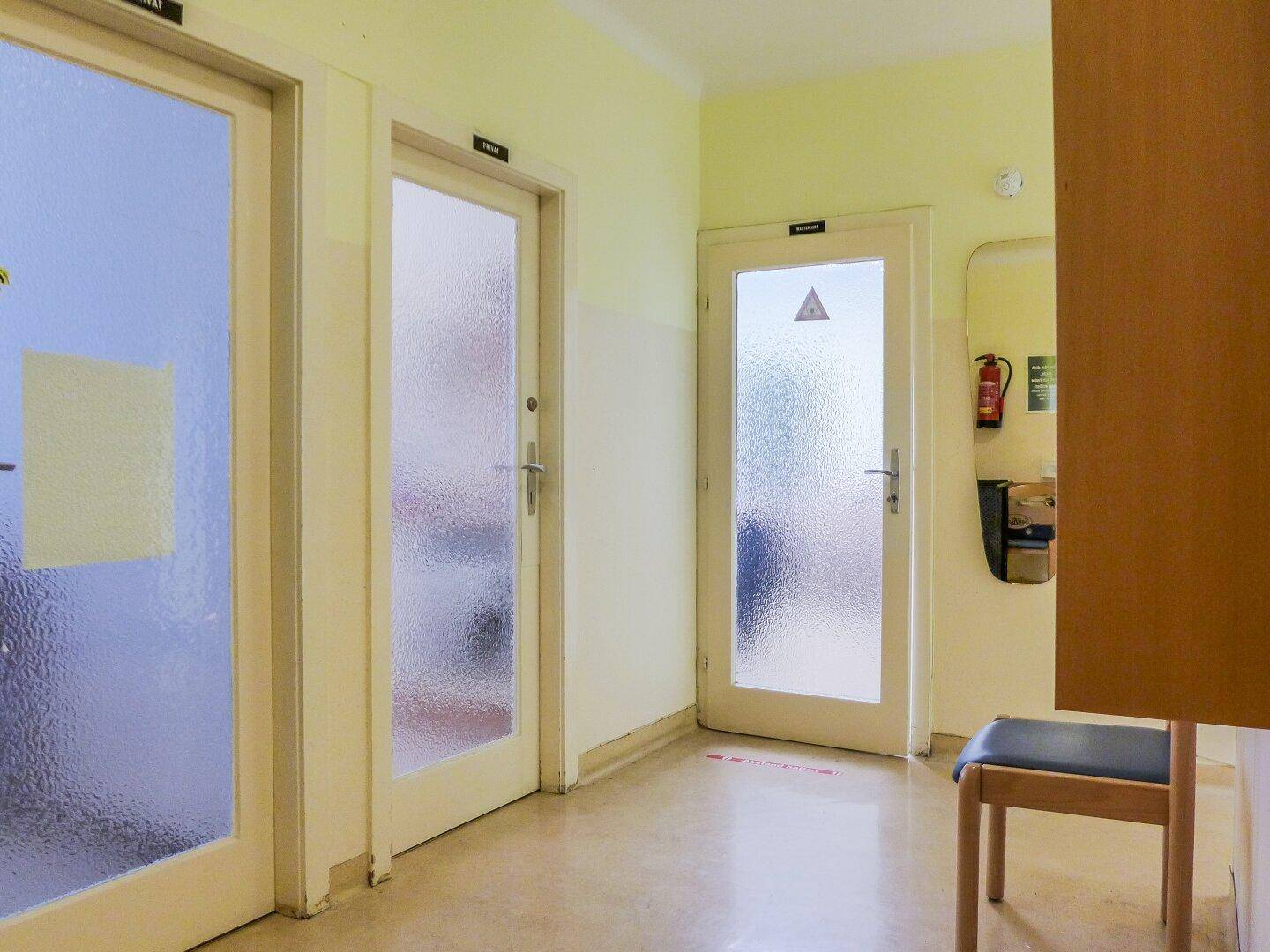 Langer Flur mit mehreren Türen, die zu verschiedenen Räumen führen, und einem Spiegel an der Wand.