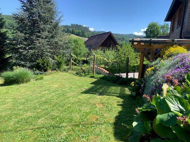 Gepflegter Garten mit Blumenbeeten und Rasenfläche, bietet einen weiten Blick in die Natur.