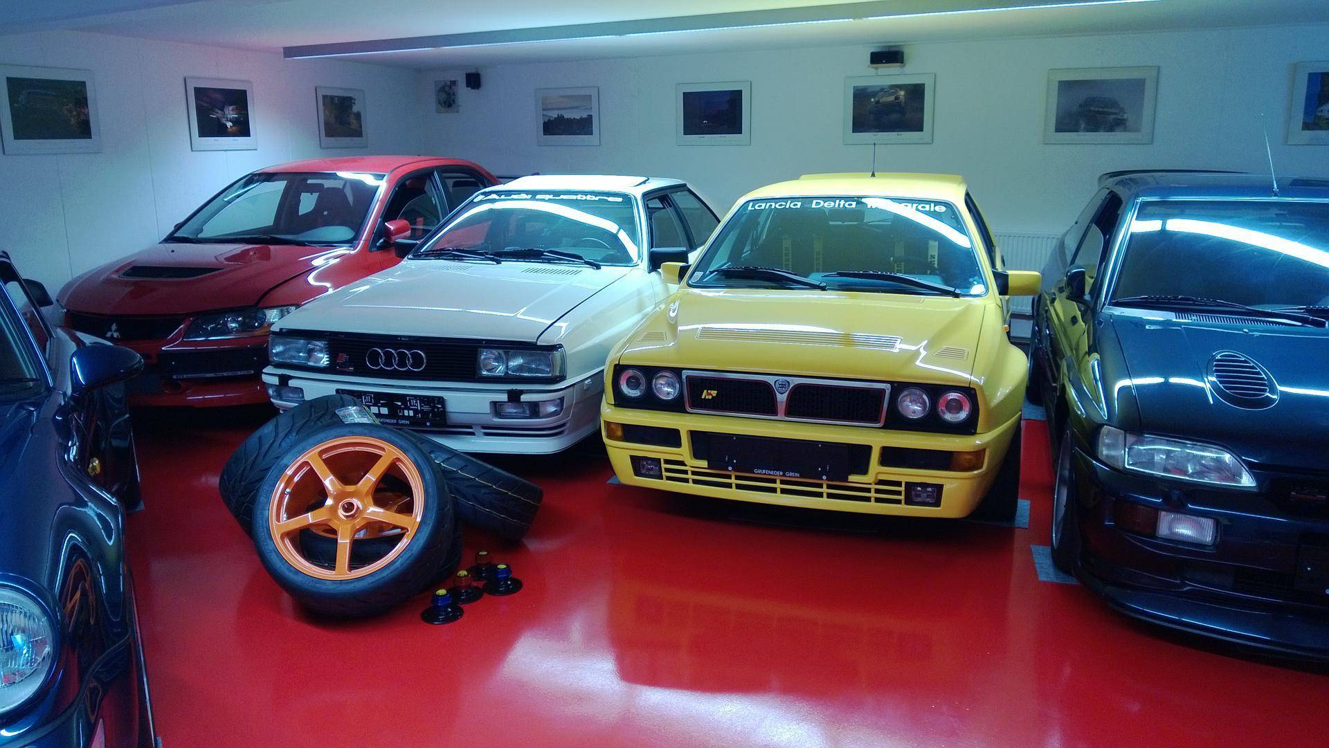 Große Garage mit mehreren Oldtimern und einem auffälligen roten Boden.