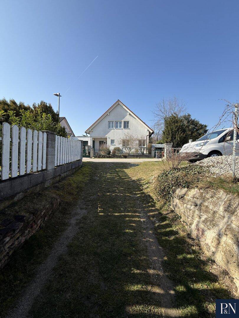 Zufahrt zum Haus mit weißem Zaun und Blick auf die Fassade.