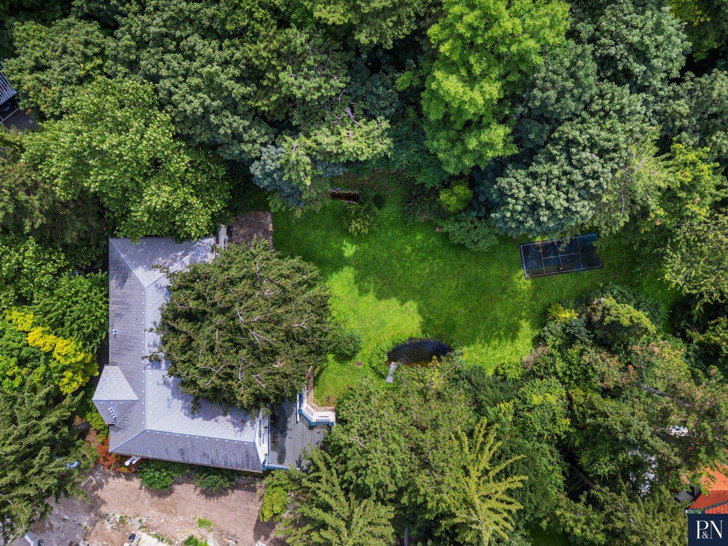 Vogelperspektive des weitläufigen Grundstücks mit Haus, Garten und Teich.