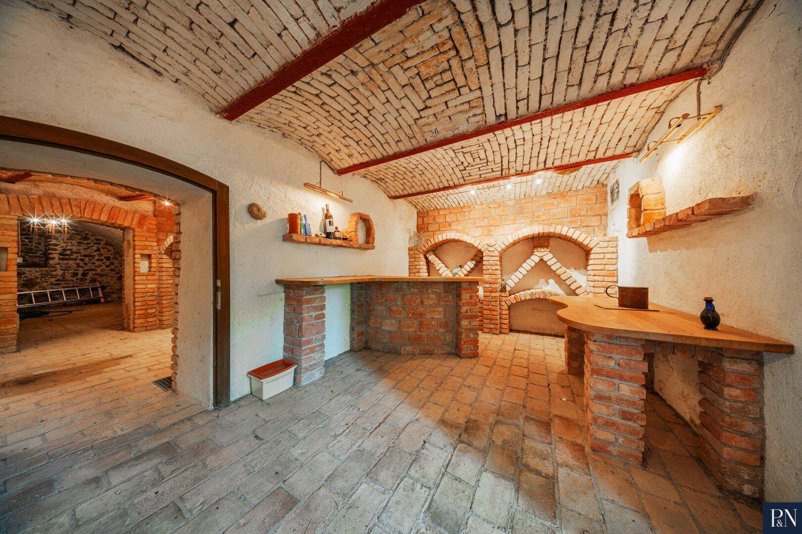 Rustikaler Weinkeller mit Ziegelgewölbe, gemauerten Regalen und traditionellem Charme.