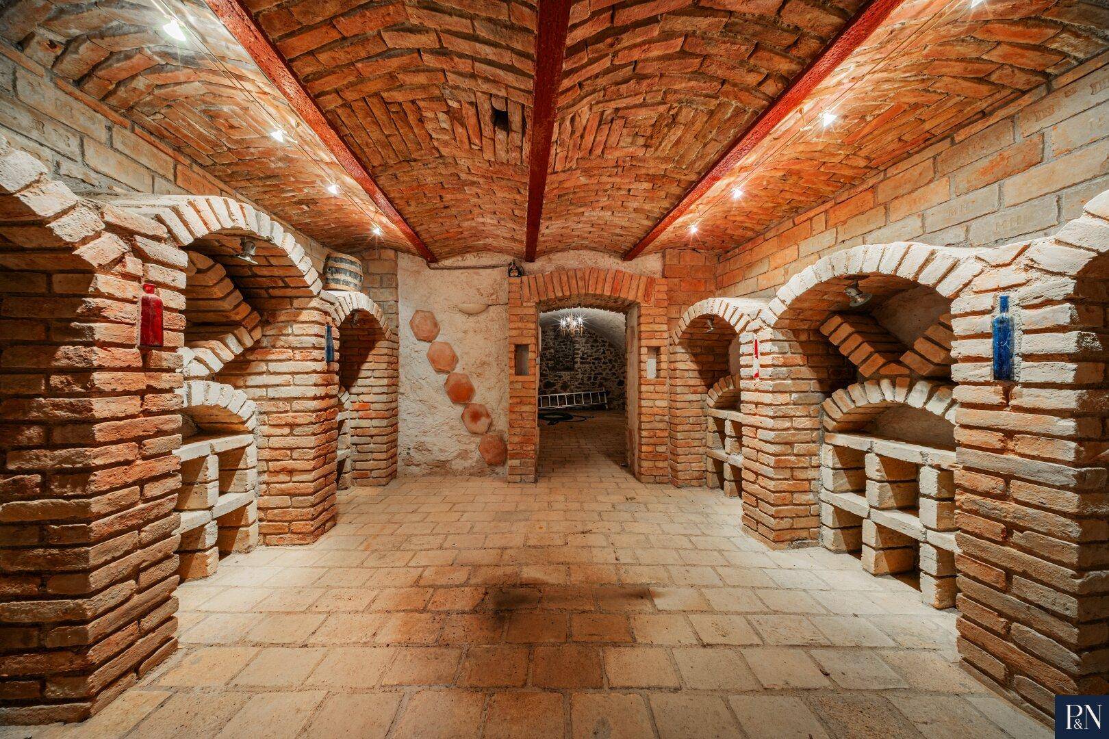 Historischer Weinkeller mit Ziegelgewölbe und gemauerten Nischen zur Weinlagerung.