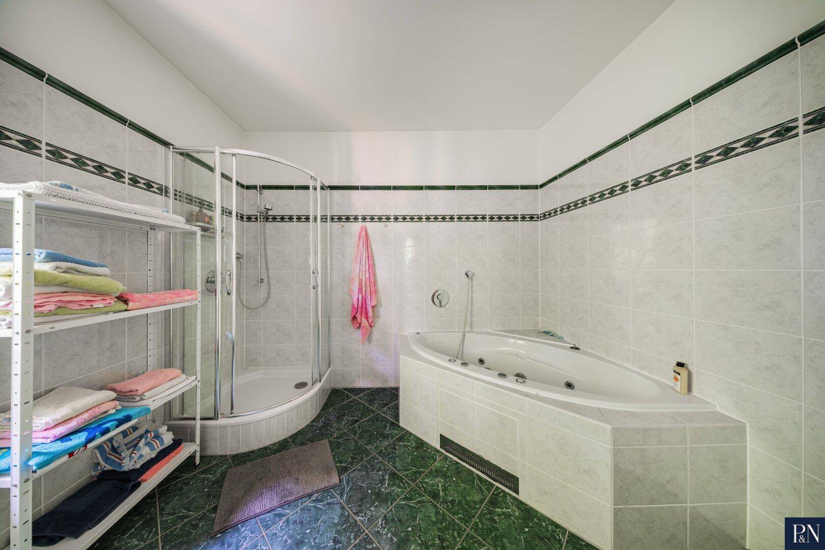 Geräumiges Badezimmer mit Duschkabine, Whirlpool und grünen Akzentfliesen.