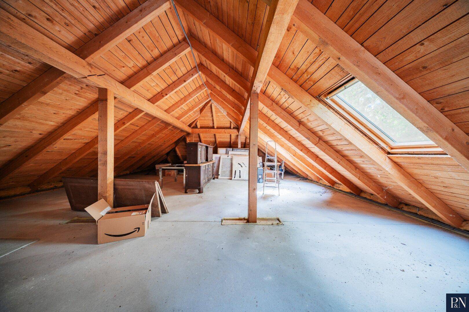 Geräumiger Dachboden mit Holzbalken, Dachfenster und Potenzial zum Ausbau.