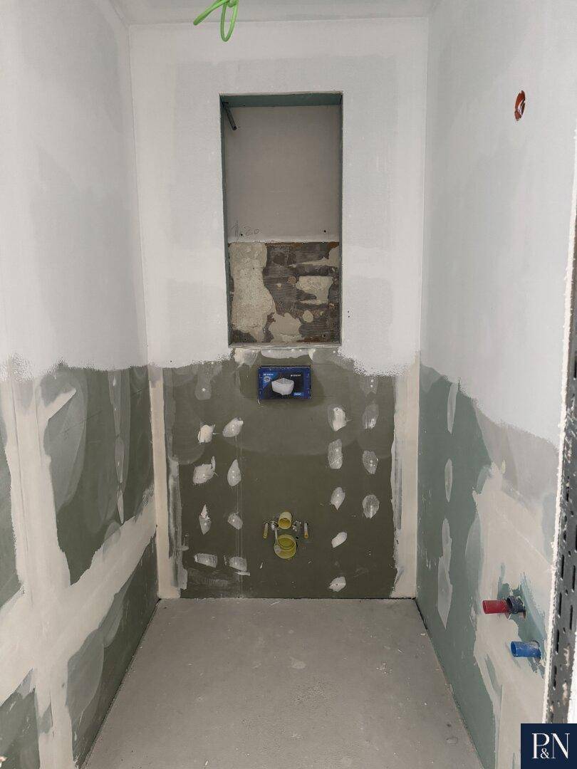 Badezimmer im Rohbau mit vorbereiteten Installationen für Toilette und Sanitäranlagen.