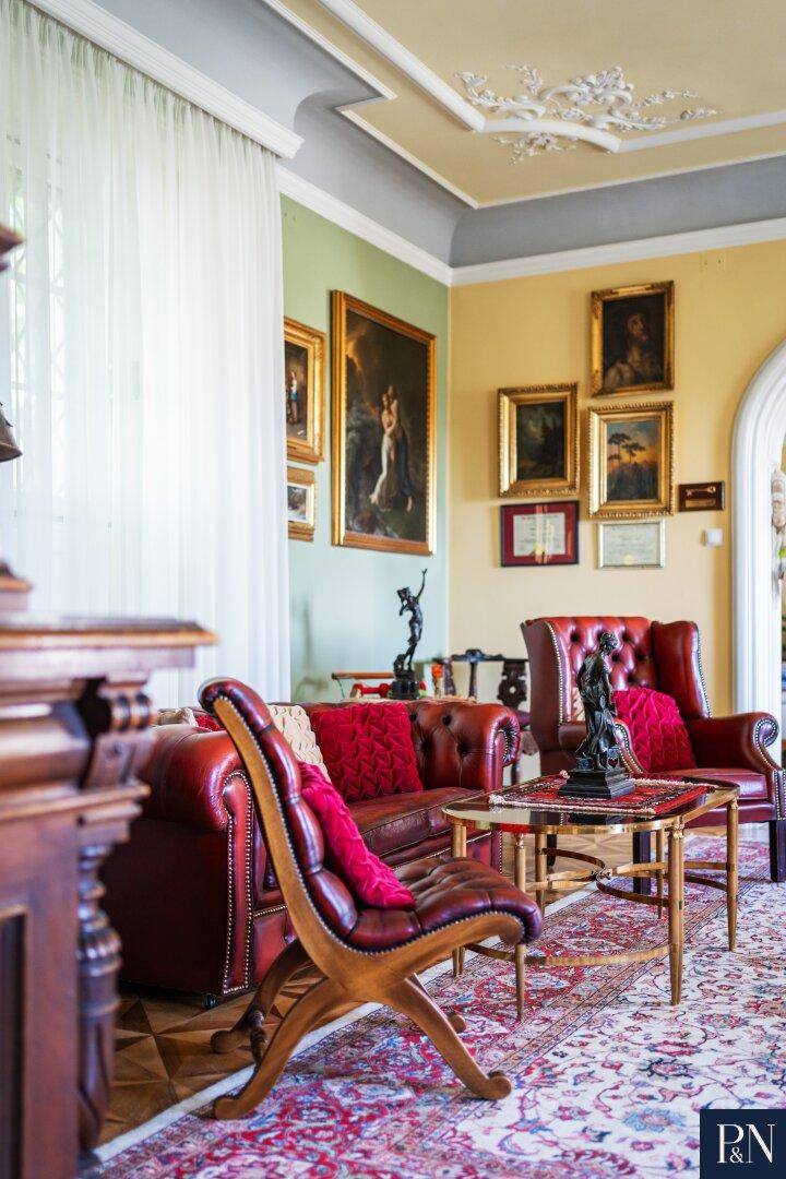 Klassisch eingerichtetes Wohnzimmer mit Ledersofas, Parkettboden und eleganten Kunstwerken an den Wänden.