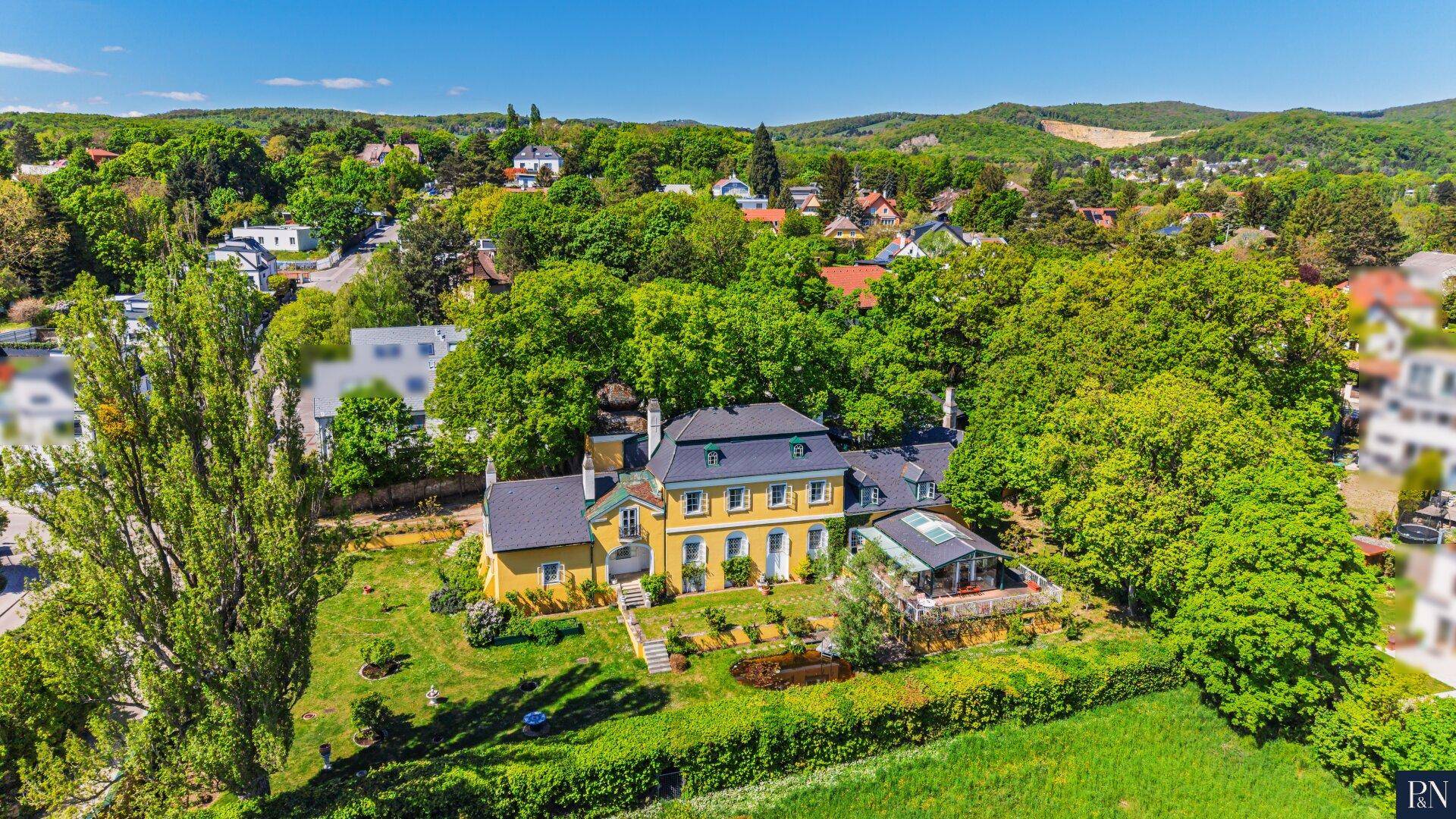 Luftaufnahme des weitläufigen Anwesens mit Hauptgebäude, Nebengebäuden und großem Gartenbereich.