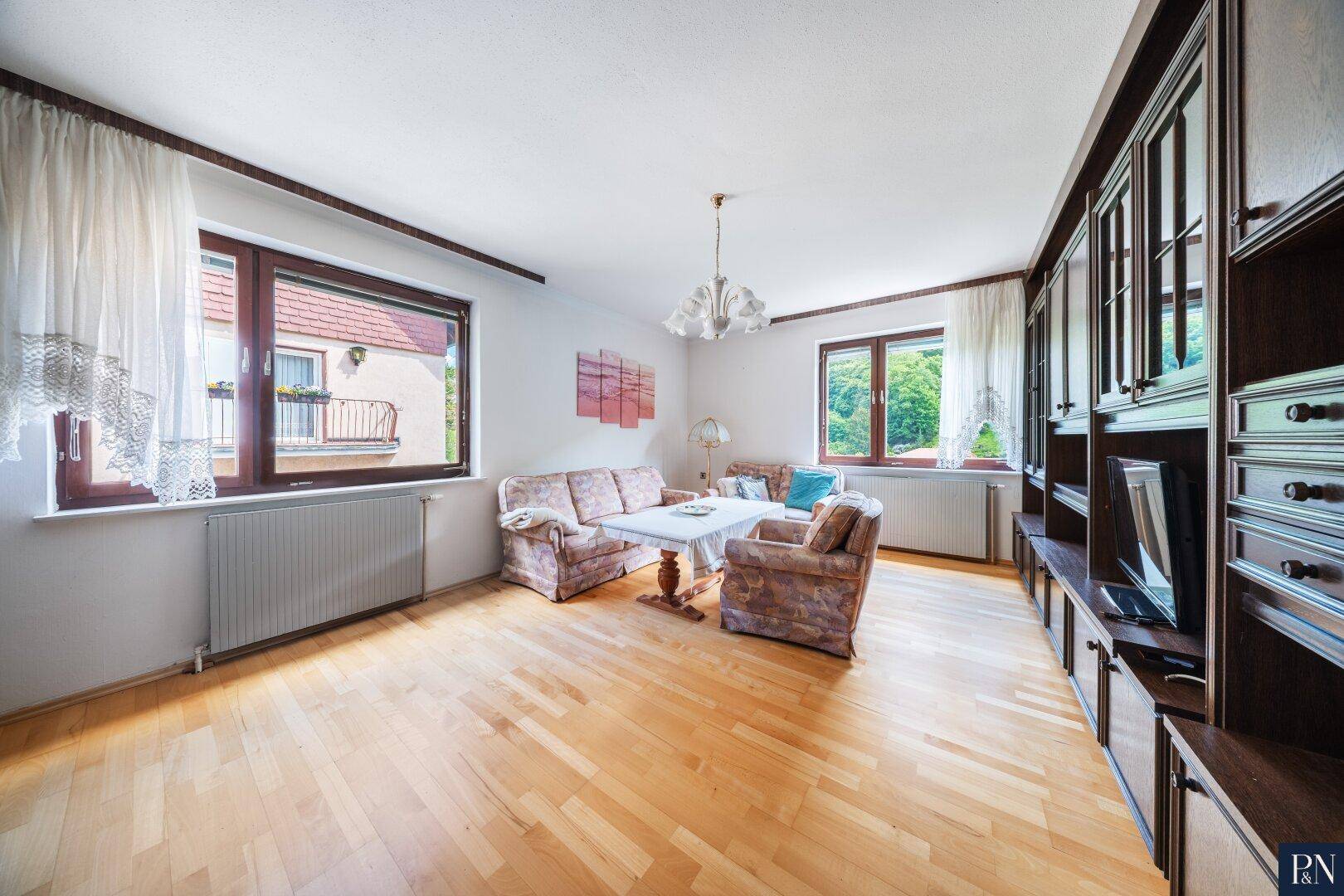 Gemütliches Wohnzimmer mit Parkettboden, traditionellen Möbeln und Blick ins Grüne.