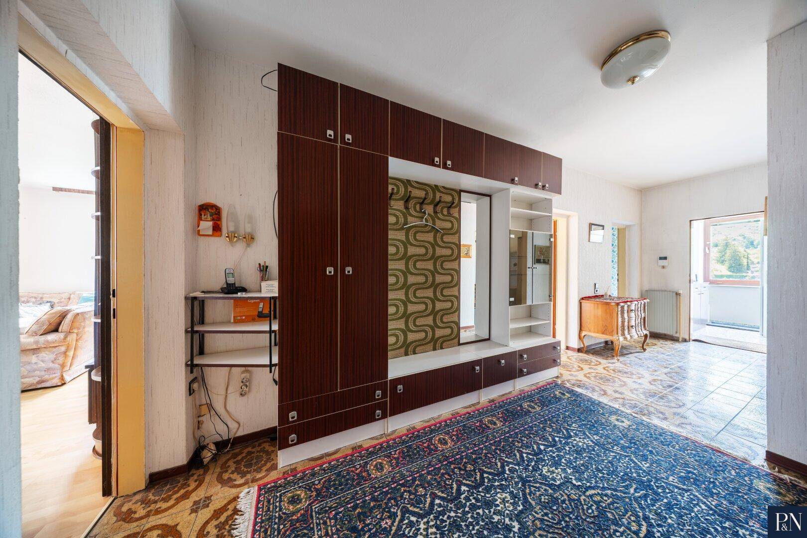 Eingangsbereich mit großem Wandschrank, Teppich und Zugang zu weiteren Räumen.
