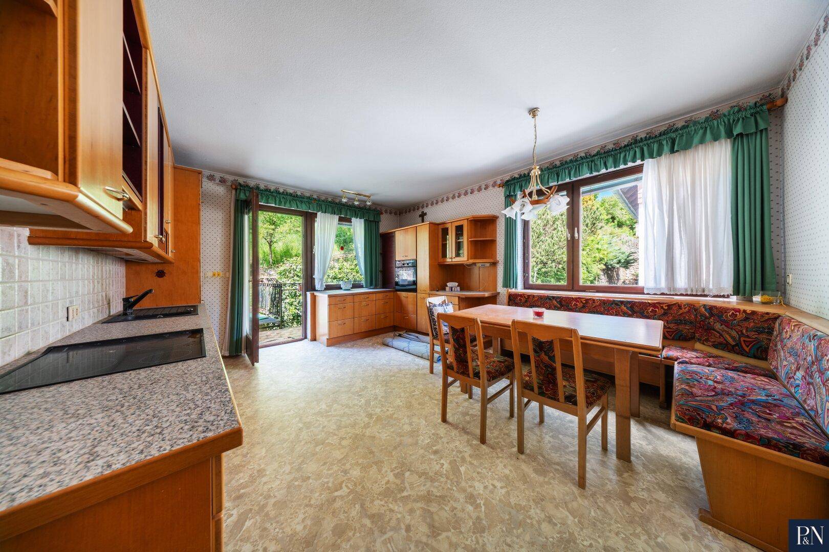 Traditionelle Küche mit Holzeinbauten, Essbereich und Zugang zu einem kleinen Balkon.