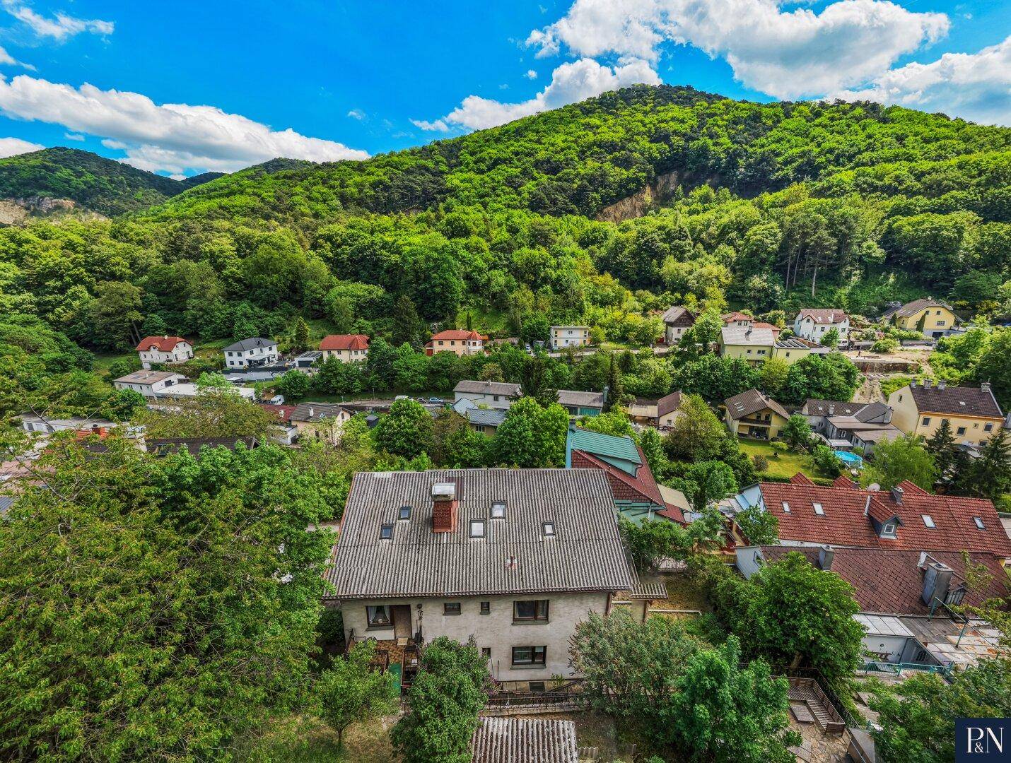 Vogelperspektive des Hauses mit Satteldach, umgeben von Bäumen und weiteren Wohnhäusern.