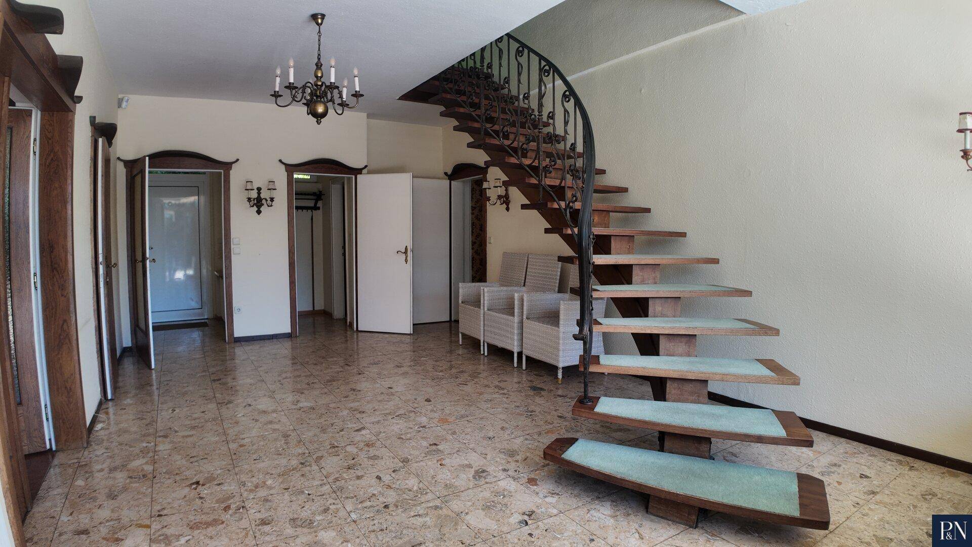 Geräumiger Eingangsbereich mit gefliestem Boden und einer eleganten geschwungenen Treppe.