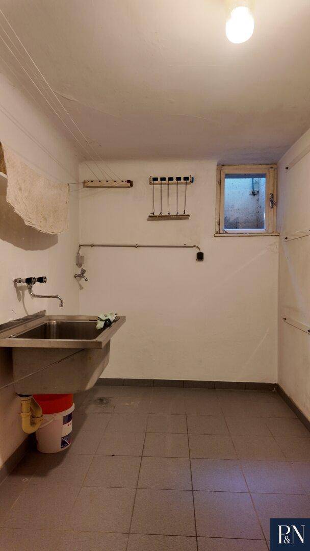 Hauswirtschaftsraum mit Waschbecken, kleinem Fenster und praktischen Aufhängemöglichkeiten.
