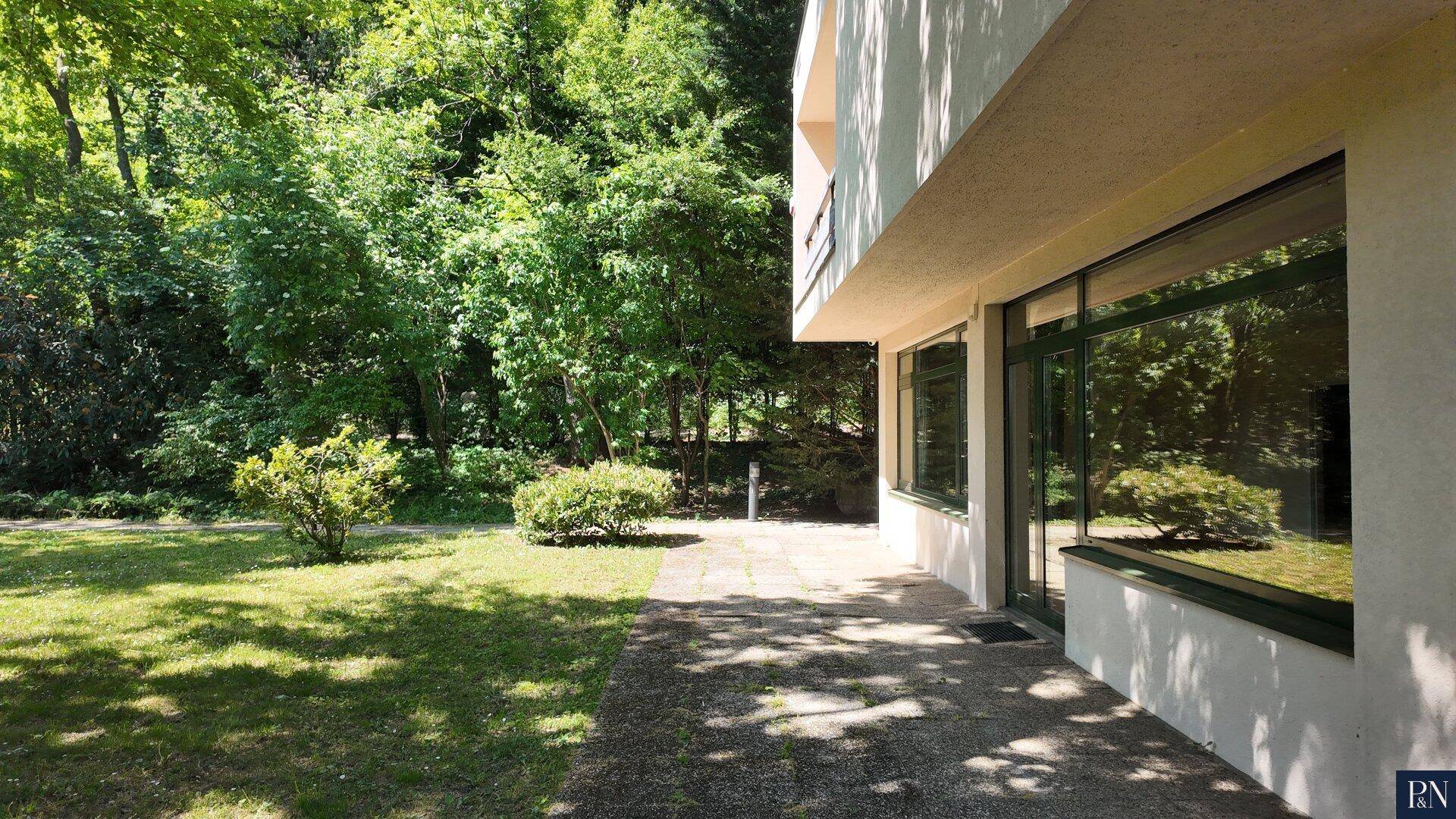 Seitlicher Blick auf das Haus mit gepflasterter Terrasse und angrenzendem grünen Gartenbereich.