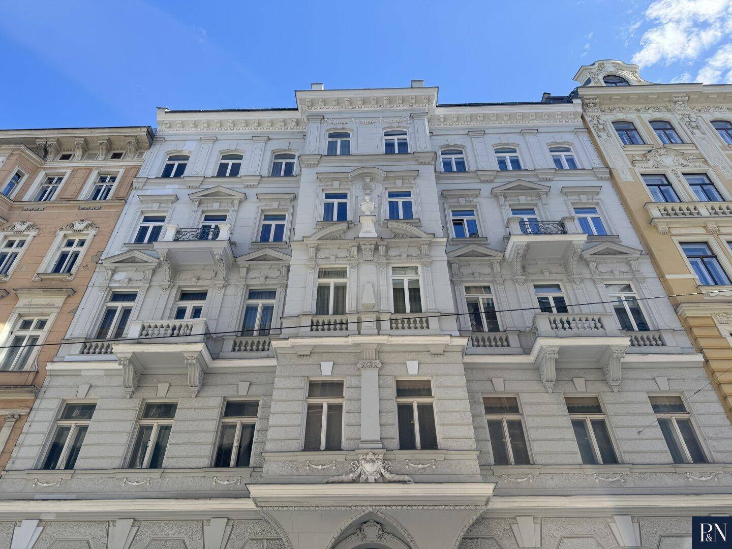 Historische Fassade eines eleganten Altbaus mit reich verzierten Balkonen und Fenstern.
