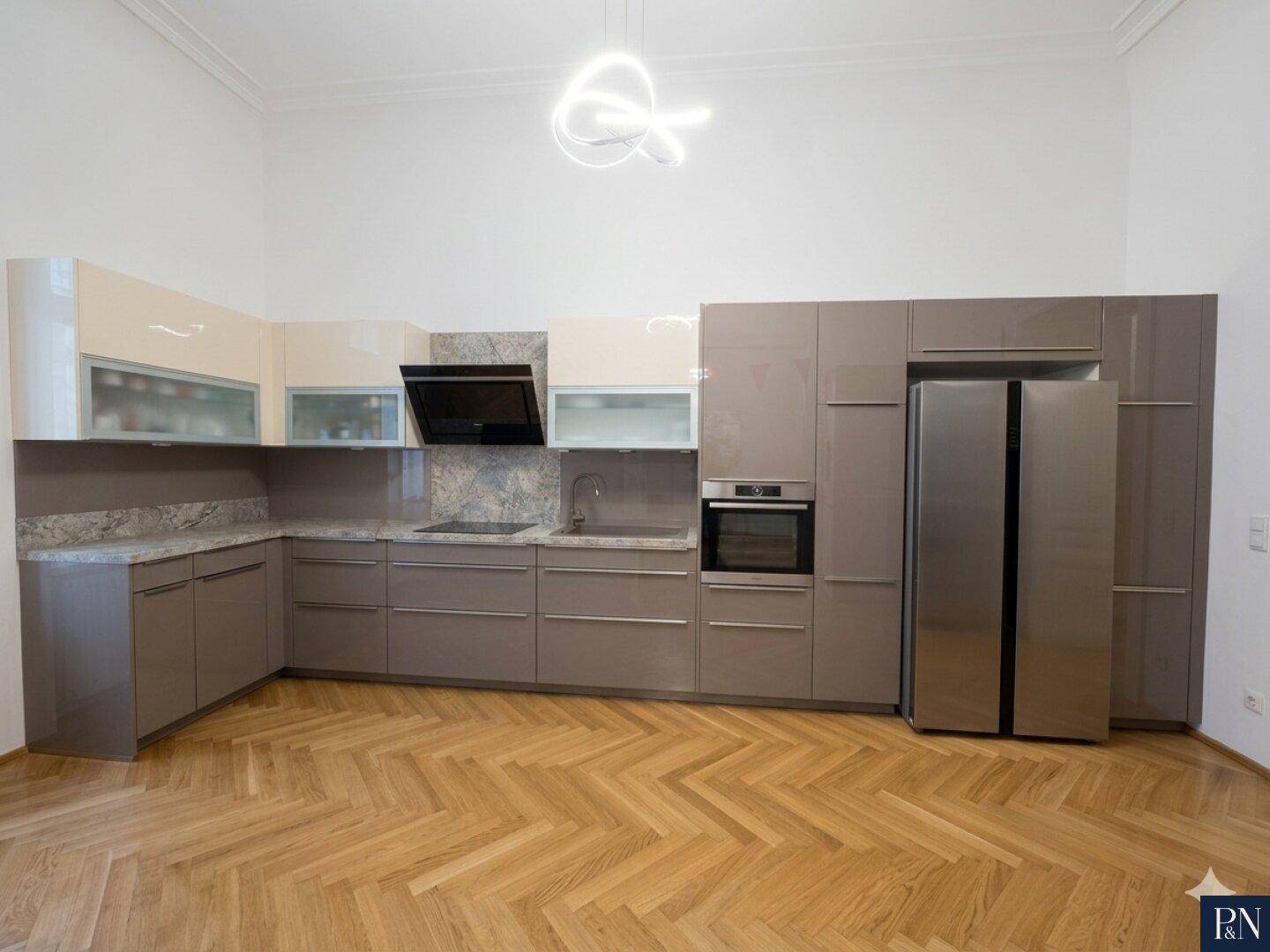 Moderne Einbauküche mit glänzenden Fronten, integrierten Geräten und viel Stauraum.
