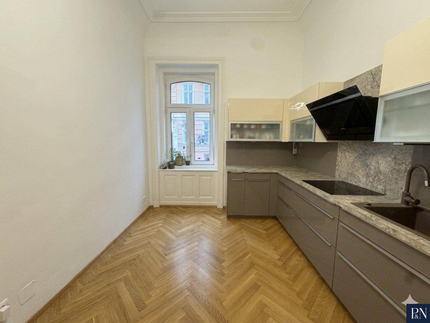 Helle Küche mit modernem Design, integrierten Geräten und einem Fenster mit Blick nach draußen.