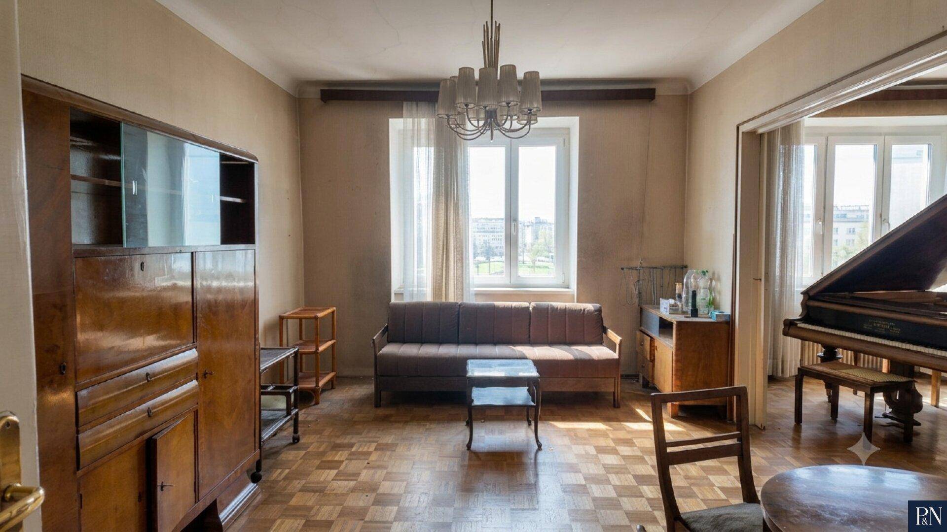 Helles Wohnzimmer mit Parkettboden, großem Fenster und klassischem Flügel.
