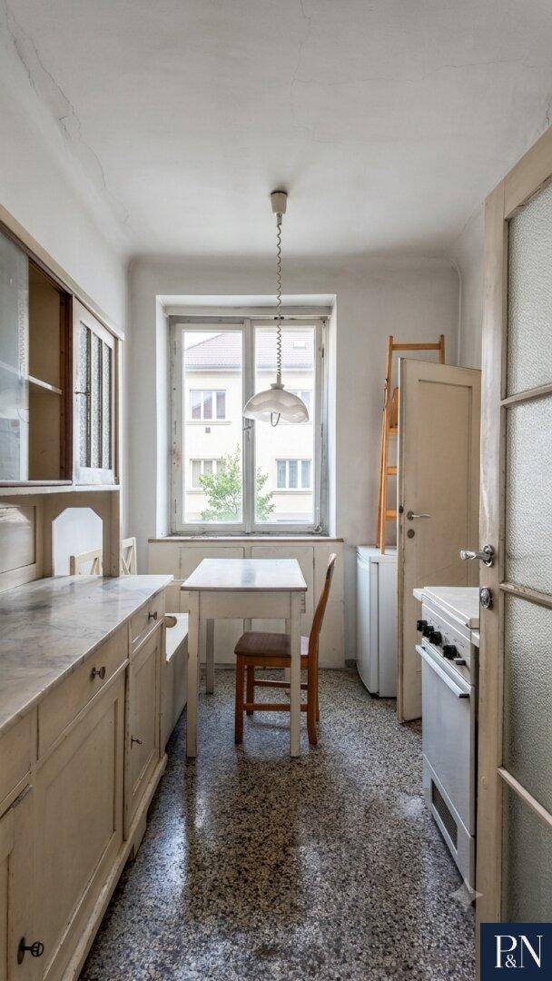 Kleine Küche mit Terrazzoboden, Einbauschränken und Fenster mit Blick ins Grüne.