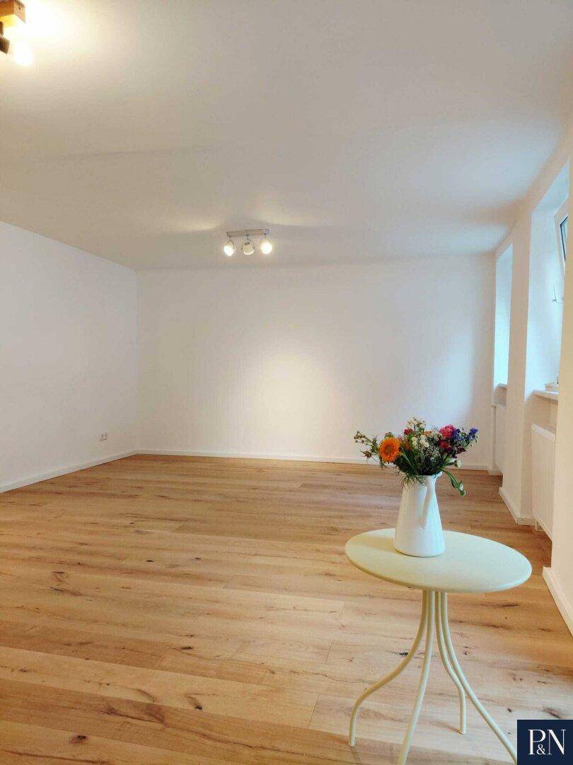 Großer, heller Raum mit Holzboden und weiß gestrichenen Wänden, bereit zur individuellen Gestaltung.