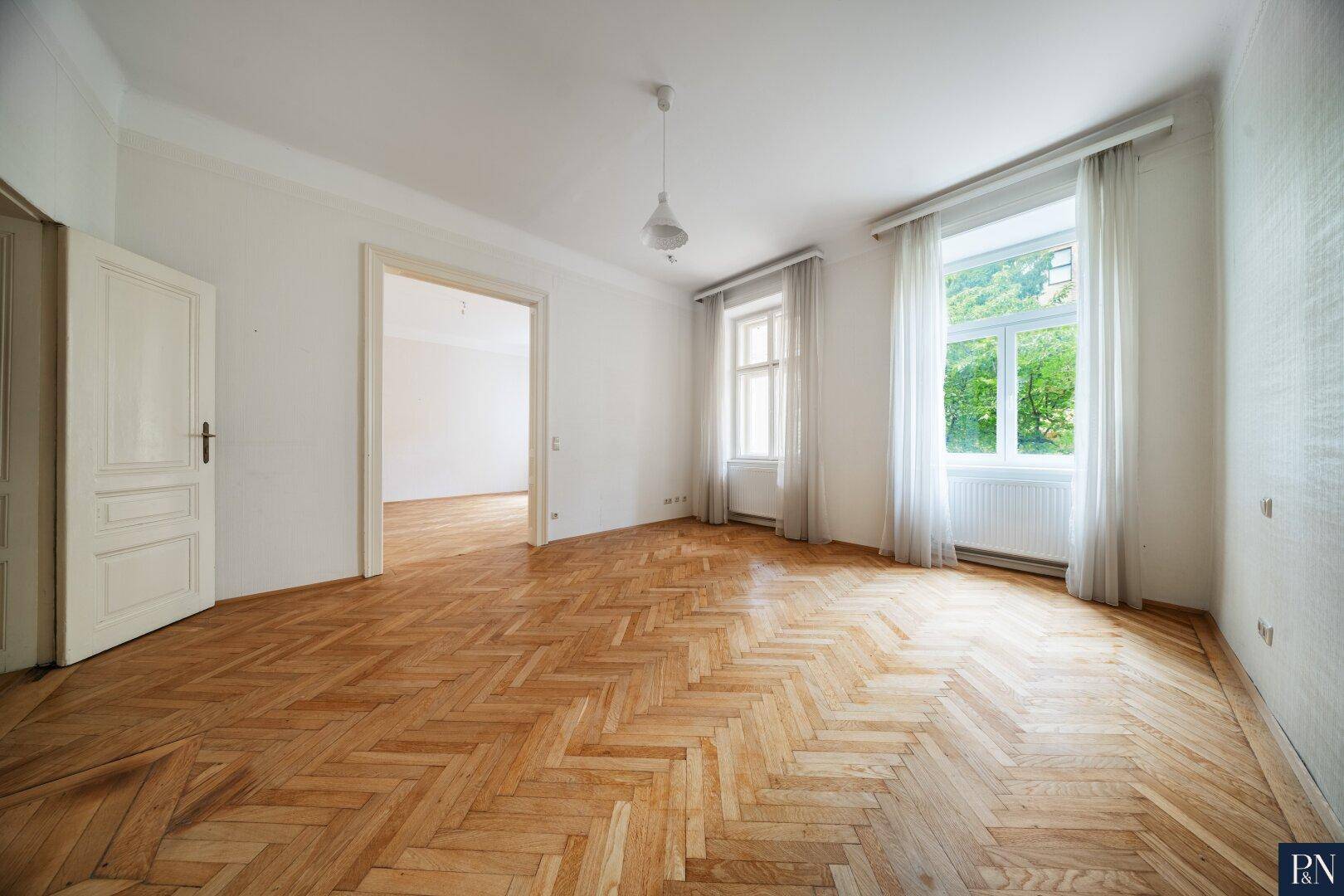 Geräumiges Zimmer mit klassischem Fischgrätparkett und hohen Decken, bereit zur individuellen Gestaltung.