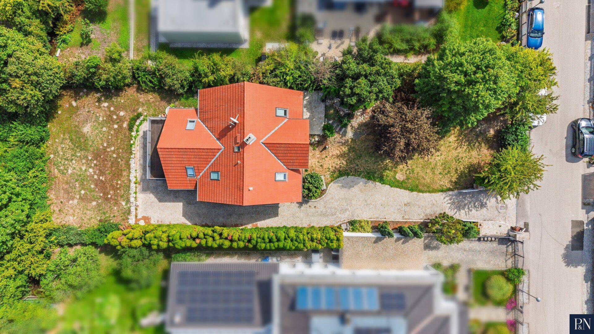 Draufsicht des Grundstücks mit Einfamilienhaus, Garten und gepflasterter Zufahrt.