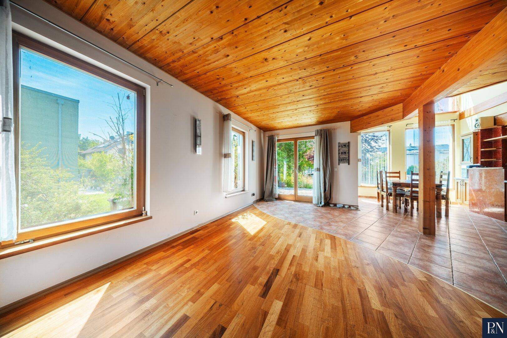Helles Wohnzimmer mit Holzbalkendecke, Parkettboden und Zugang zum Garten.