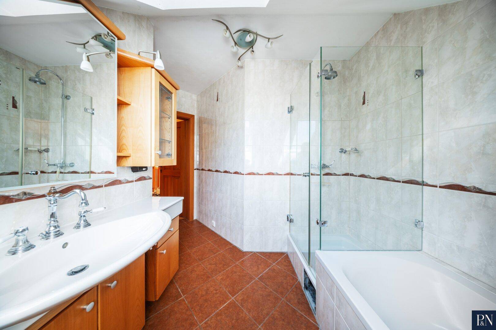 Badezimmer mit Dusche, Badewanne, Waschtisch und Spiegelschrank.