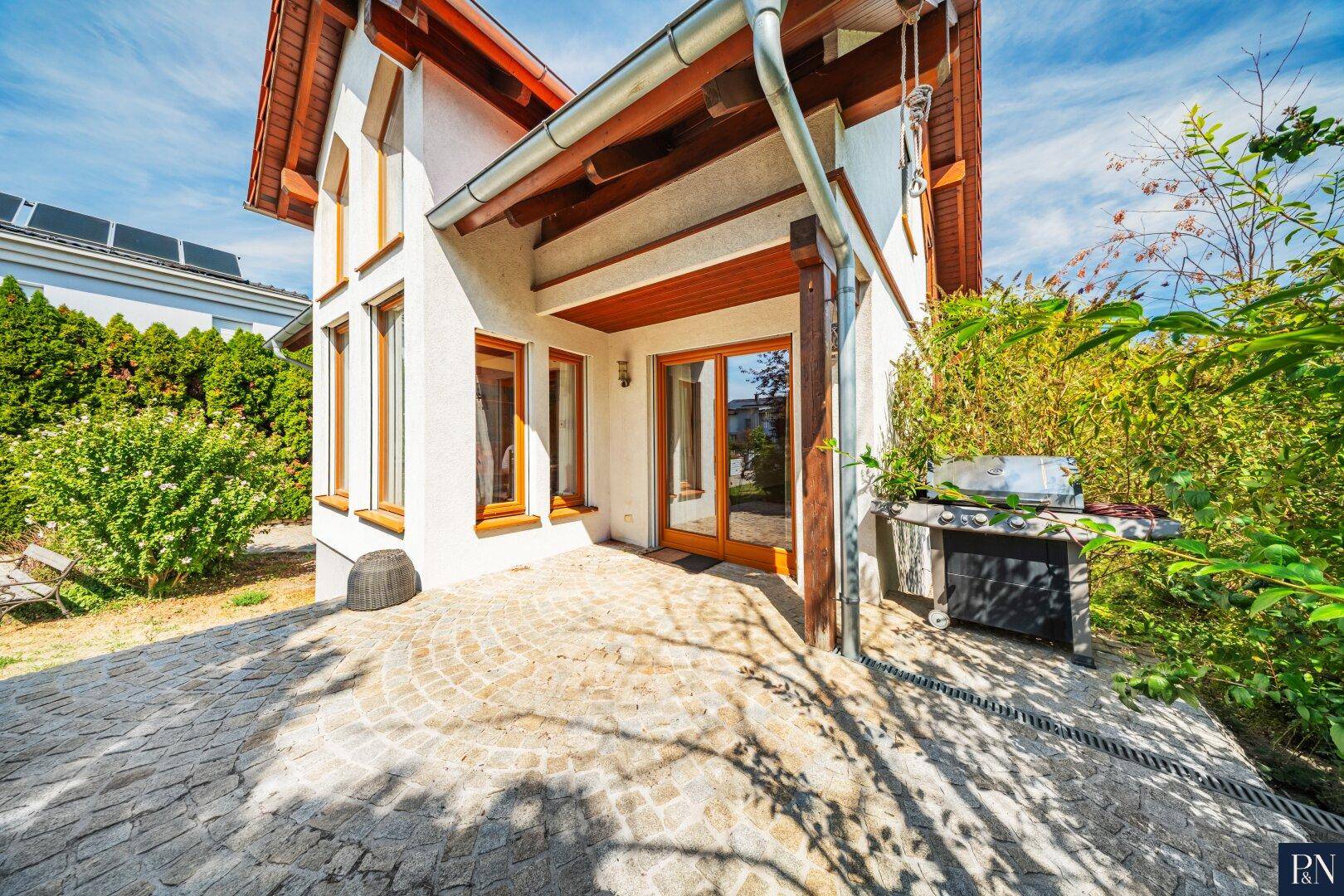 Gemütliche Terrasse mit Pflastersteinen und integriertem Grillbereich.