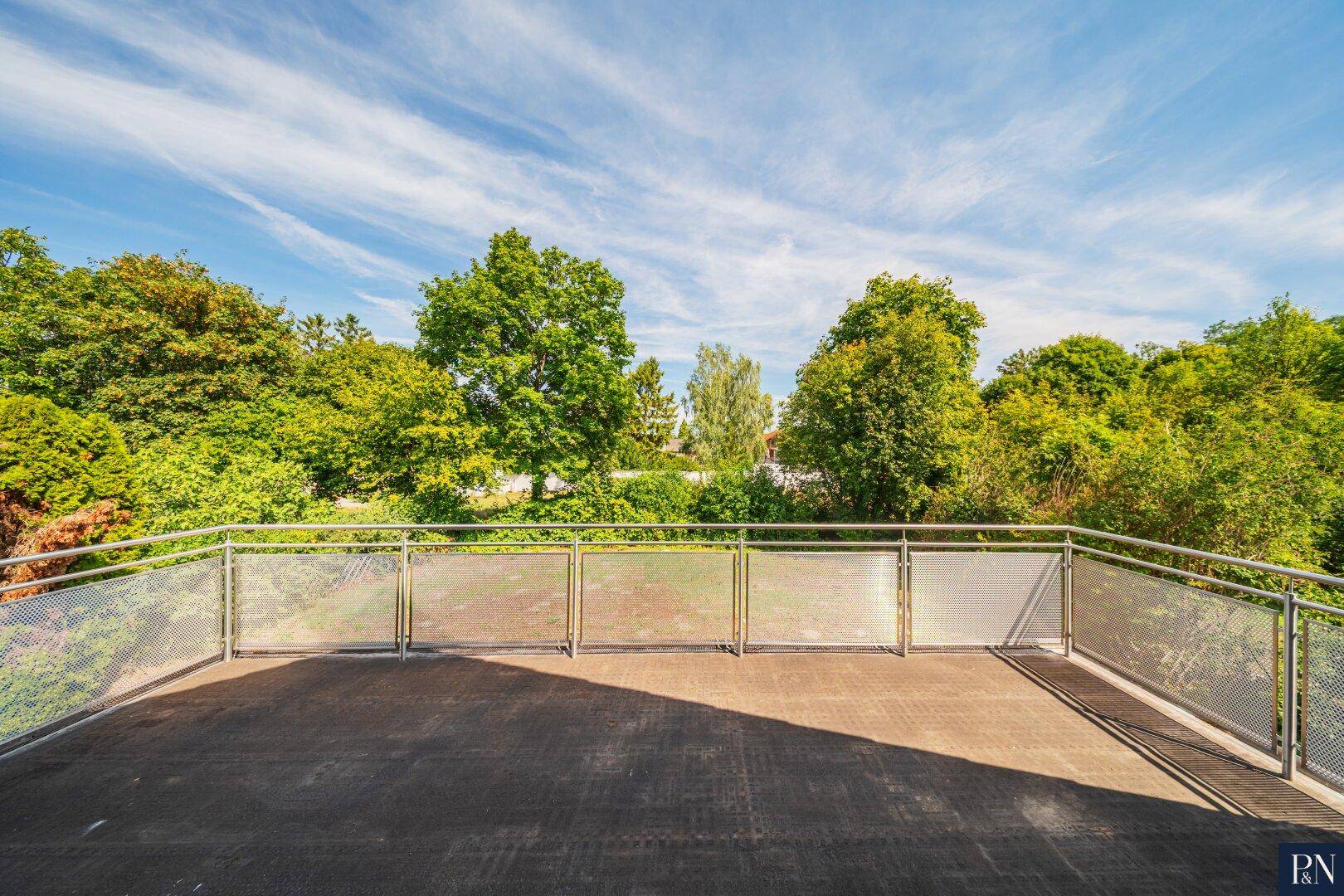 Großer Balkon mit Metallgeländer und weitem Blick ins Grüne.
