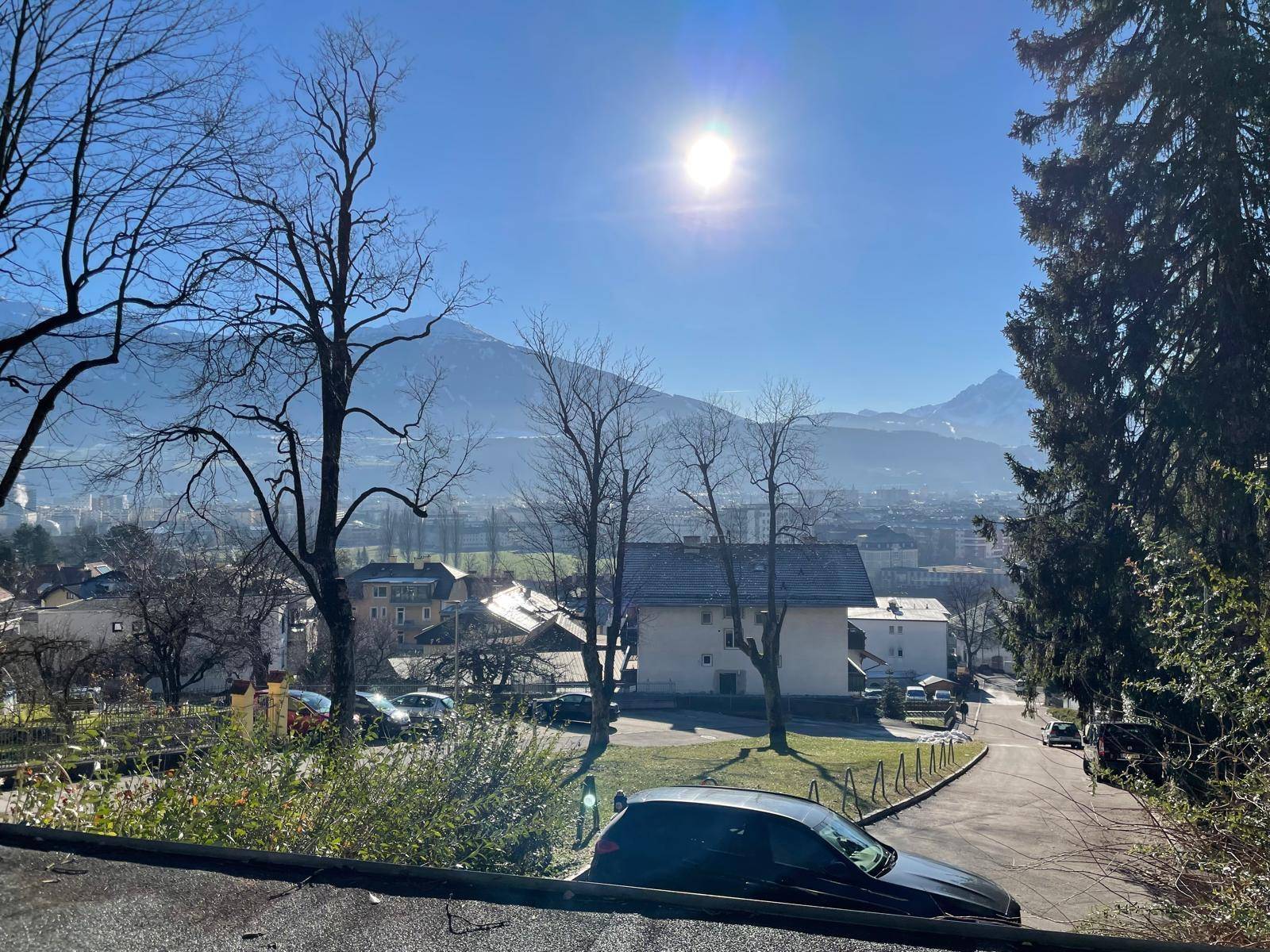 Panoramablick auf eine Stadt und die majestätischen Berge unter einem strahlend blauen Himmel.