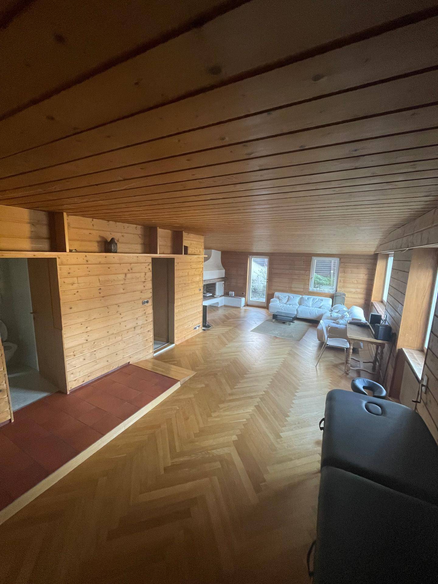 Gemütlicher Raum mit Holzvertäfelung an Wänden und Decke sowie klassischem Fischgrätparkettboden.
