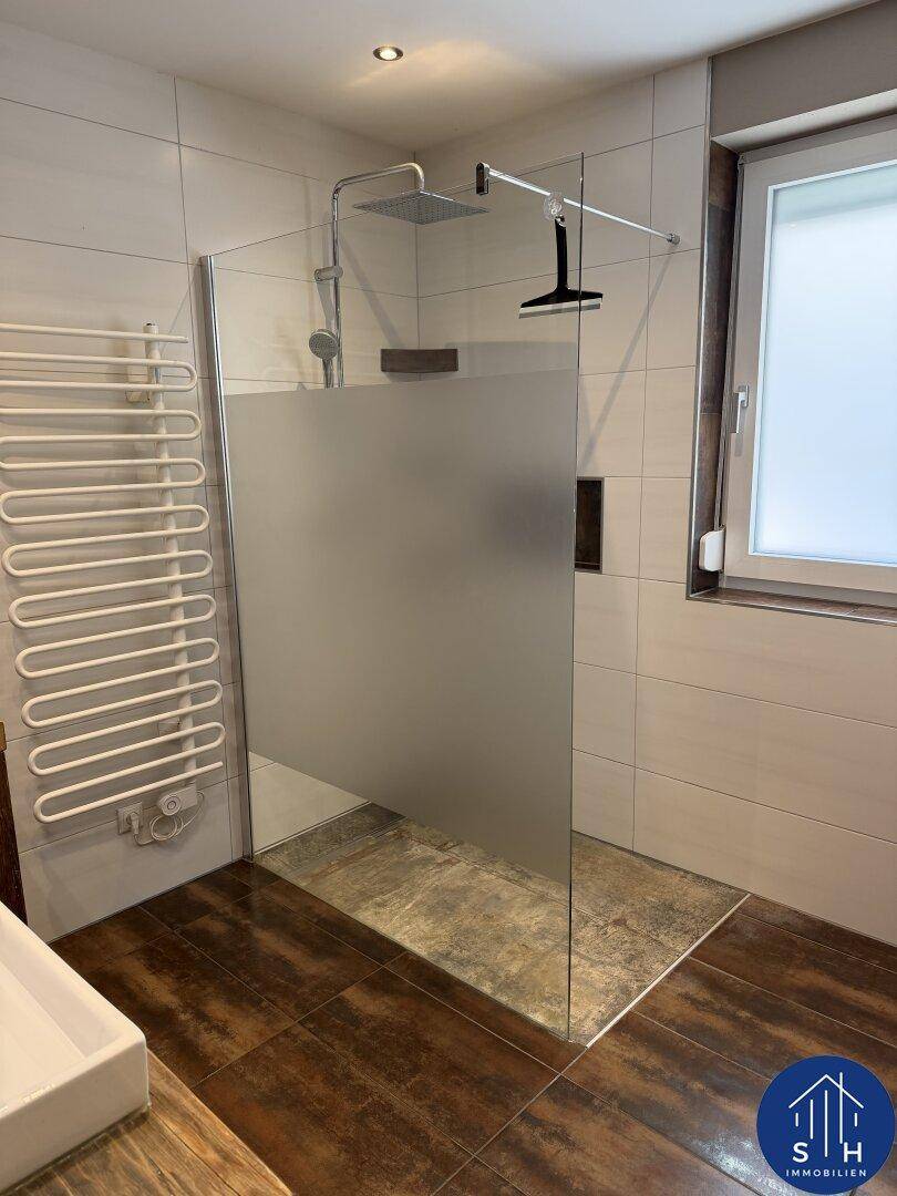 Helles Badezimmer mit begehbarer Dusche, Handtuchheizkörper und einem Fenster für gute Belüftung.