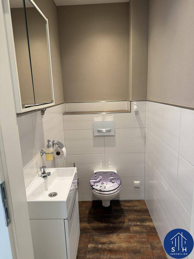 Kleines Gäste-WC mit modernem Waschbecken, wandhängender Toilette und Spiegelschrank.