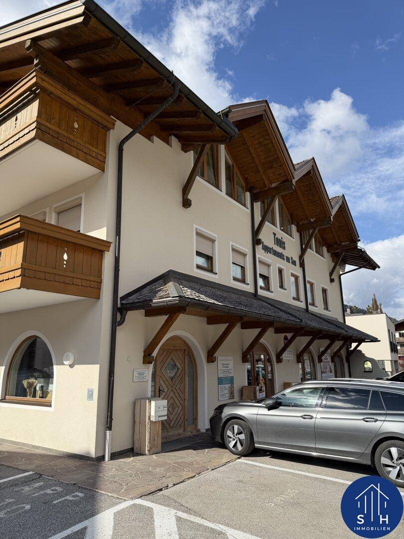 Charmantes Gebäude mit traditioneller Holzarchitektur und Parkmöglichkeiten unter blauem Himmel.