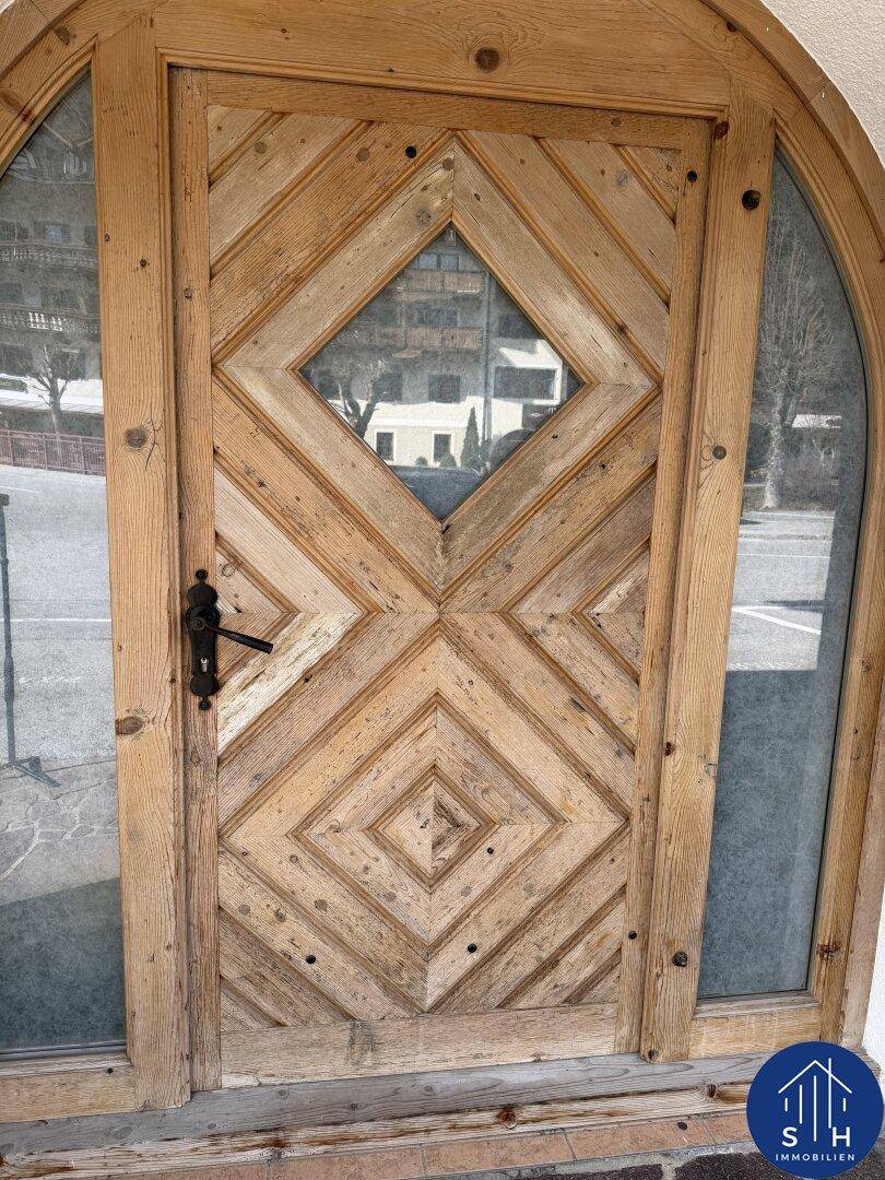 Detailaufnahme einer kunstvoll gestalteten Holztür mit Rautenmuster und Glaselementen.