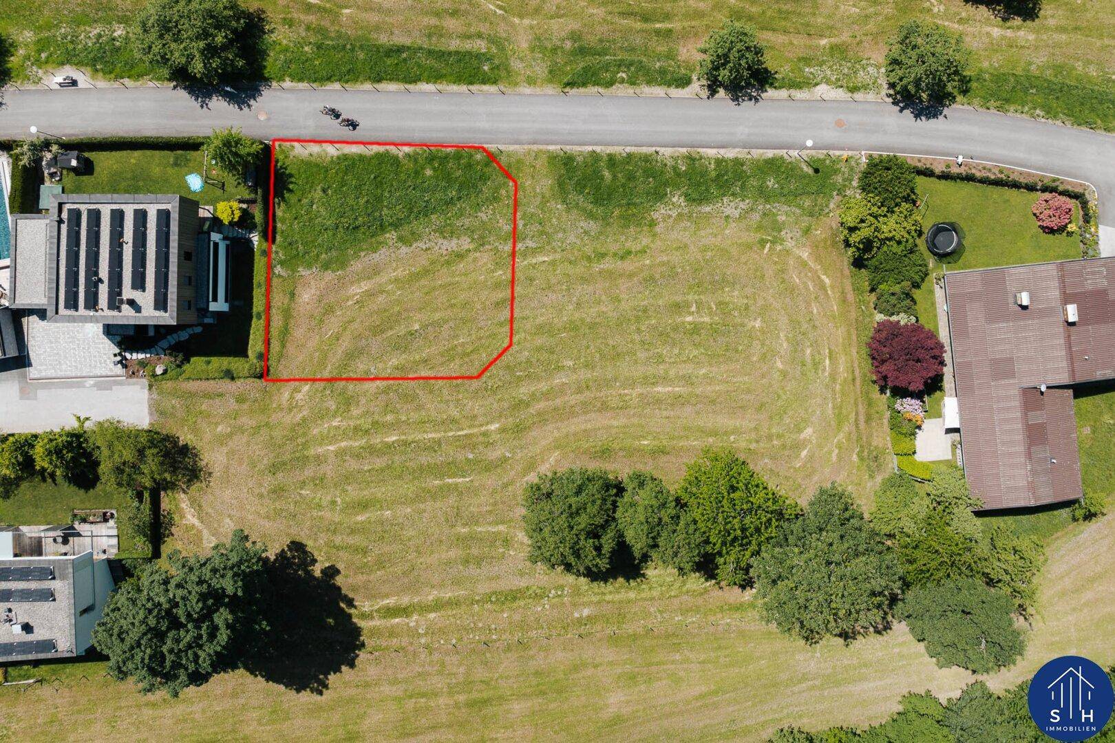 Luftbild des Baugrundstücks mit roter Markierung der Grenzen und angrenzender Straße.