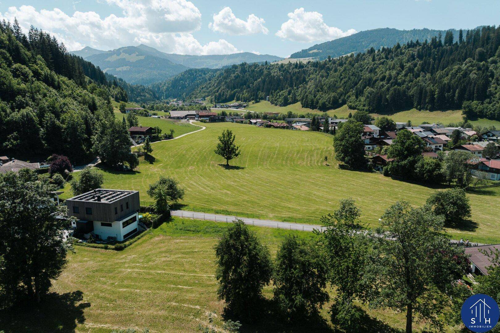 Luftaufnahme eines modernen Hauses in einem grünen Tal mit einem malerischen Dorf.