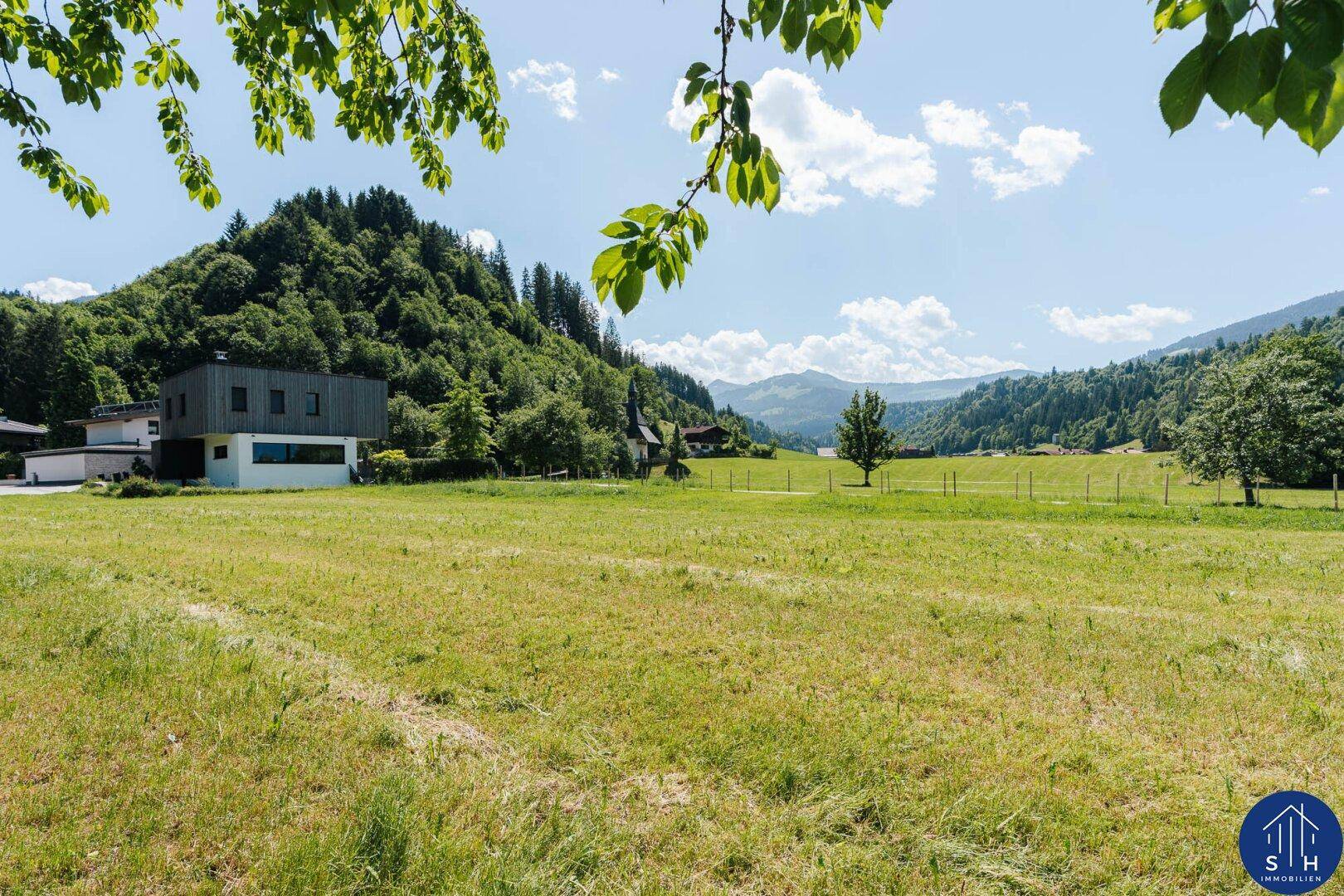 Modernes Gebäude am Rande einer Wiese mit weitem Blick auf die Bergkette.
