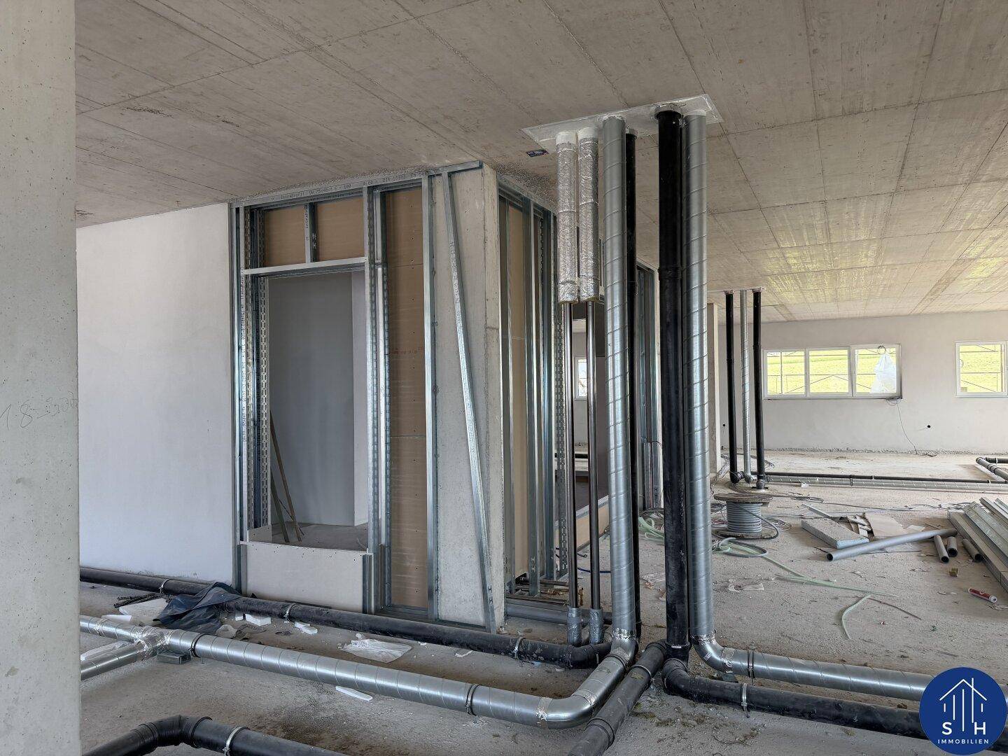 Rohbau-Innenansicht mit Lüftungsrohren, Installationsschächten und vorbereiteten Wandstrukturen für den Ausbau.