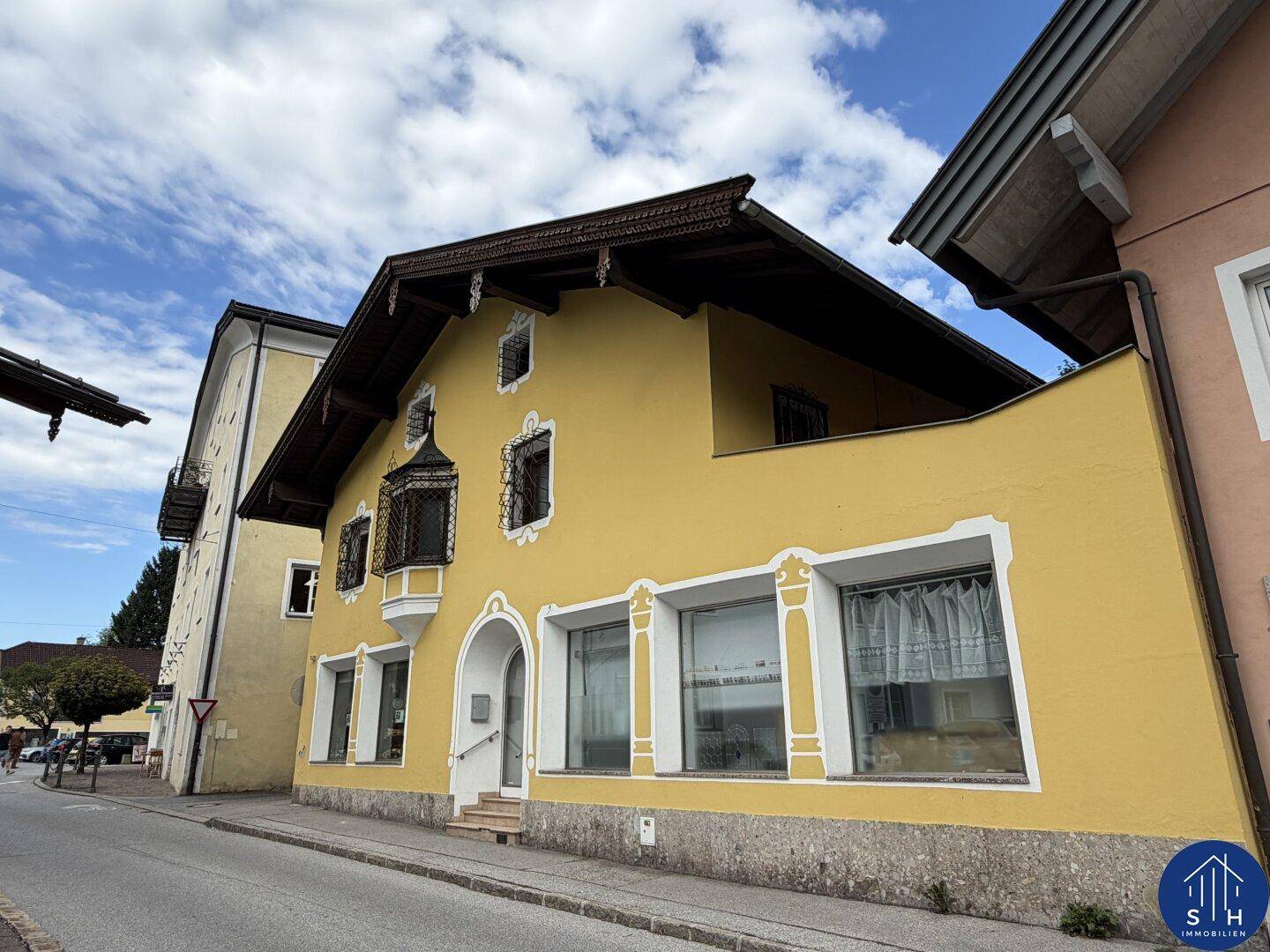 Gelbes Gebäude mit traditioneller Architektur, Erker und großen Fenstern entlang einer Straße.