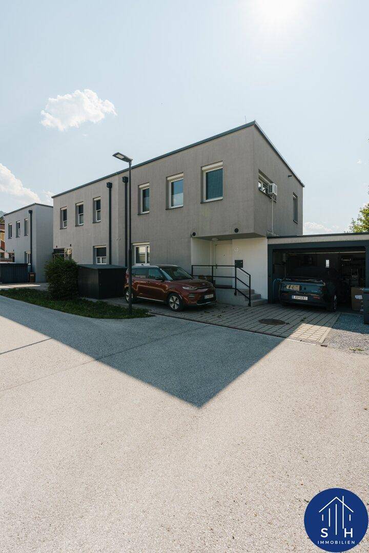 Außenansicht eines modernen grauen Hauses mit integrierter Garage und gepflasterter Auffahrt.