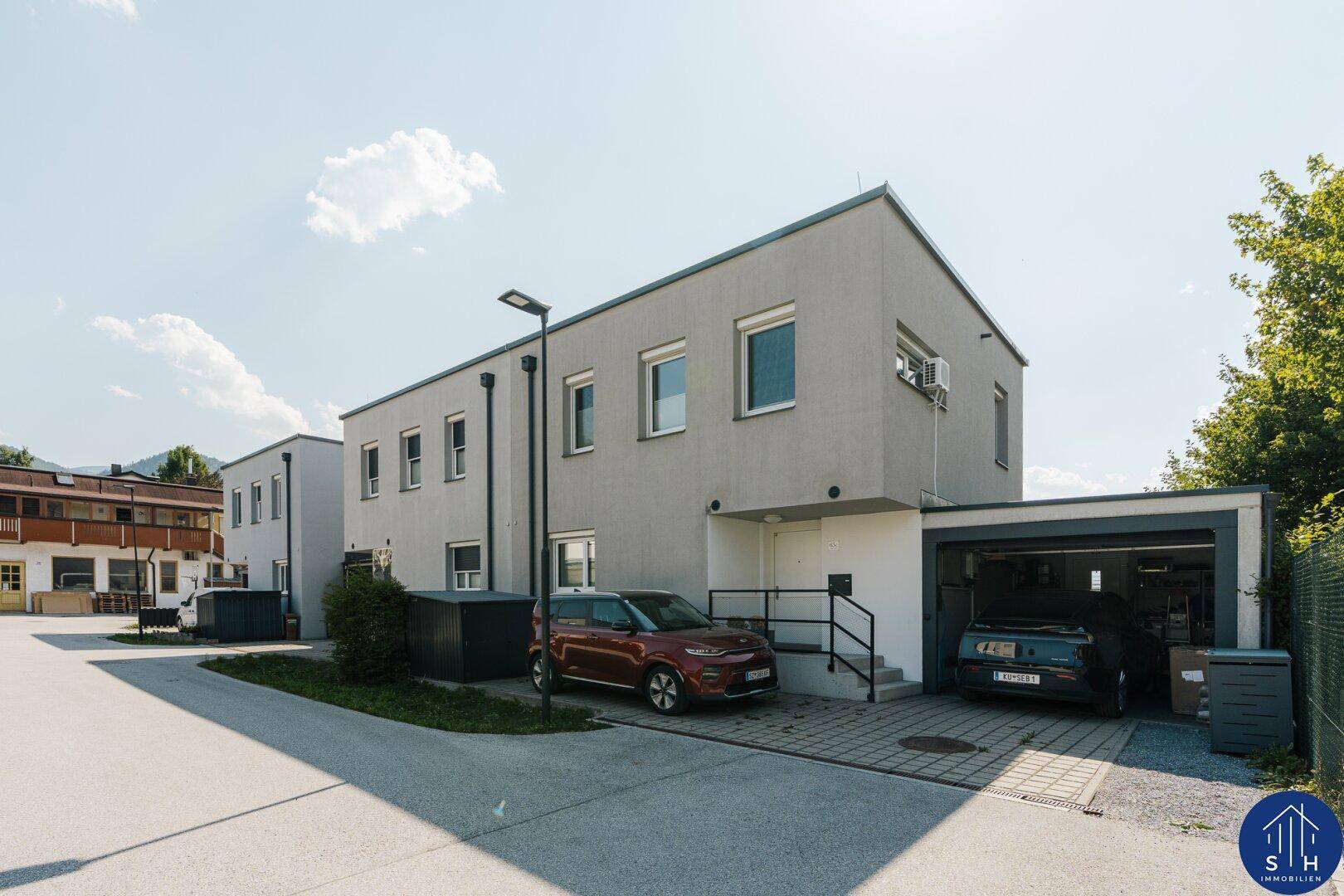 Ansicht eines modernen Einfamilienhauses in Grau mit Garage und Stellplatz im Freien.