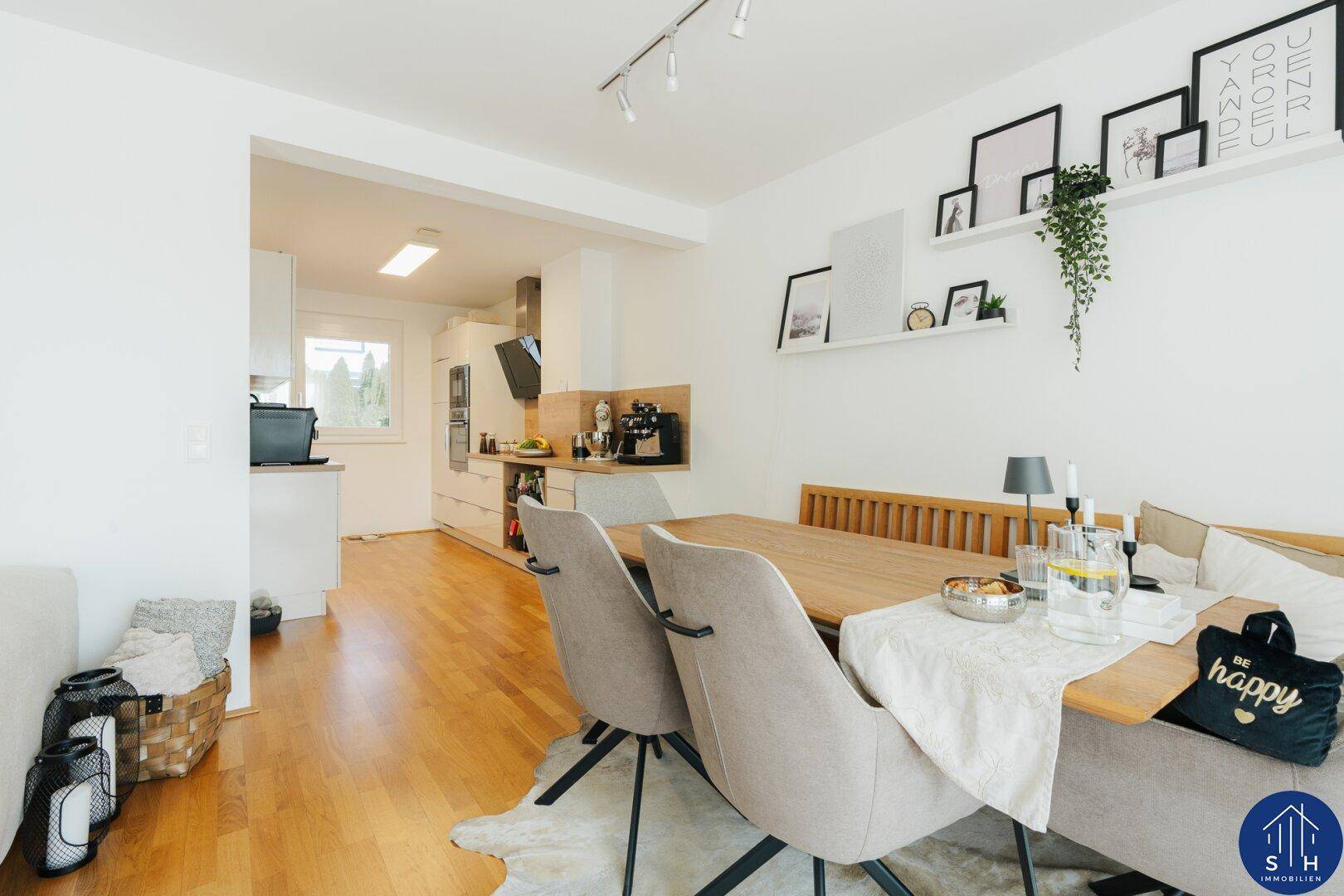 Heller Essbereich mit Holztisch und modernen Stühlen, offen zur angrenzenden Küche.