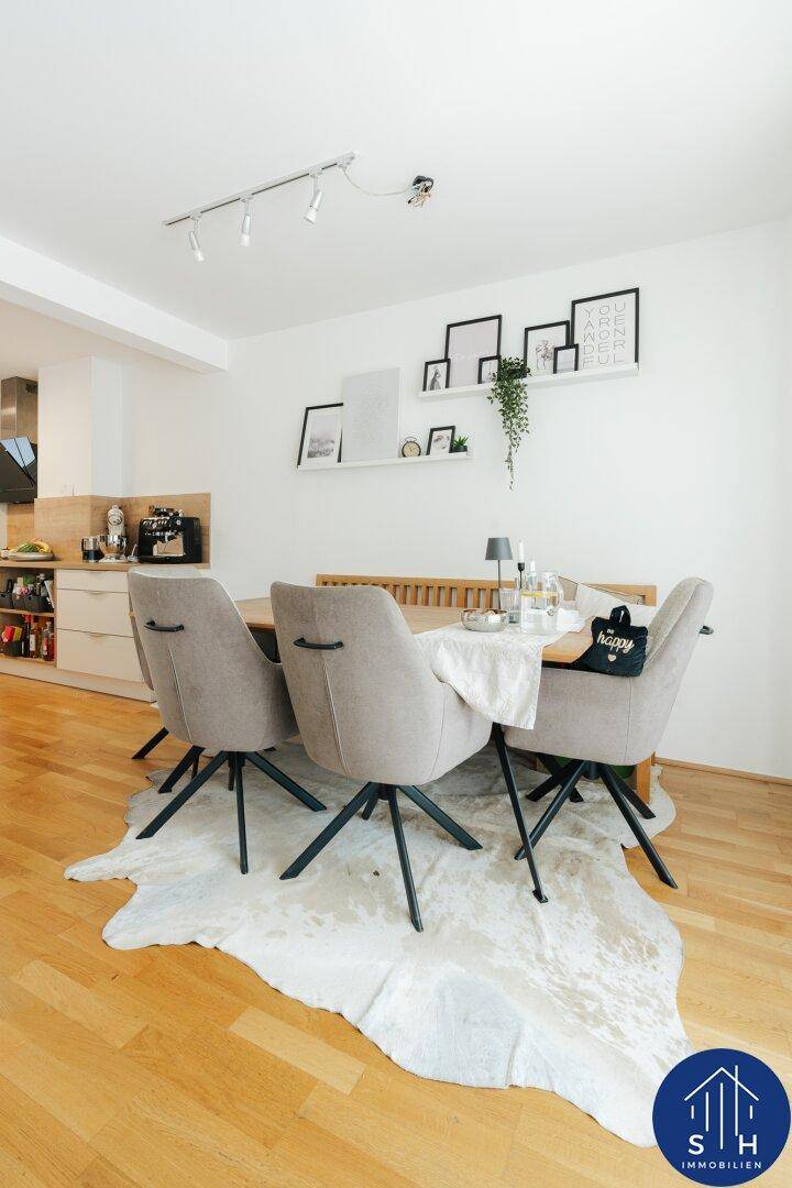 Moderner Essbereich mit Holztisch, bequemen Stühlen und einem Teppich, offen zur Küche.