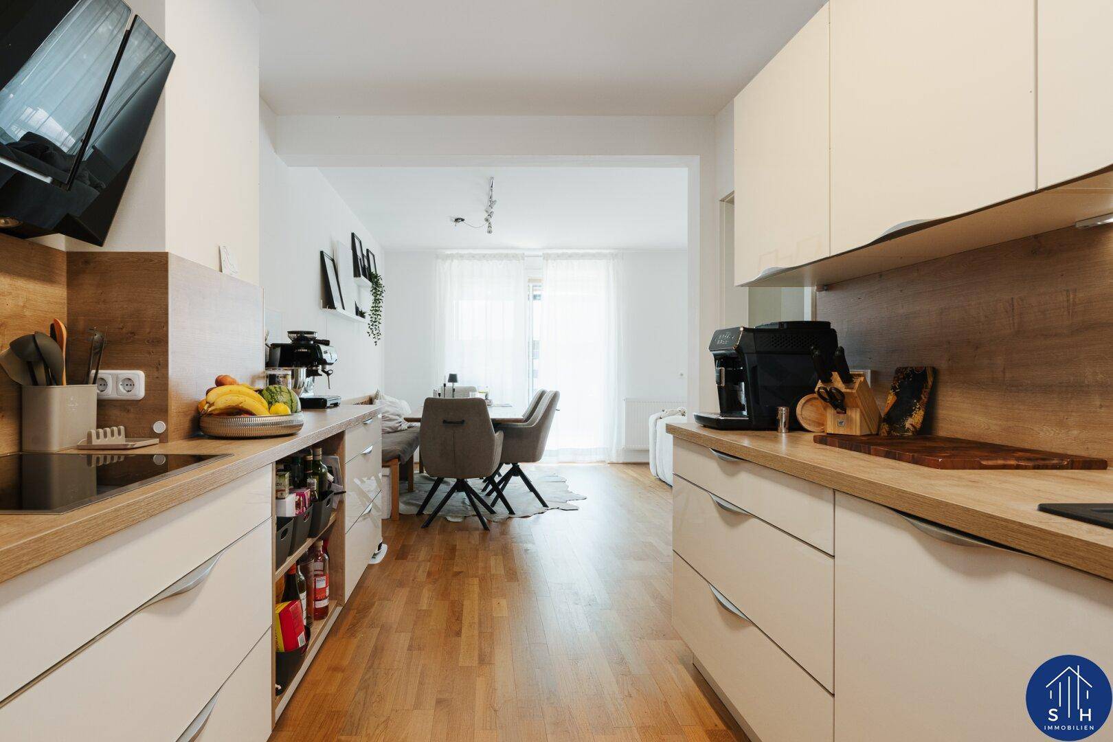Moderne Küche mit hellen Holz-Arbeitsplatten und weißen Schränken, offen zum Essbereich.
