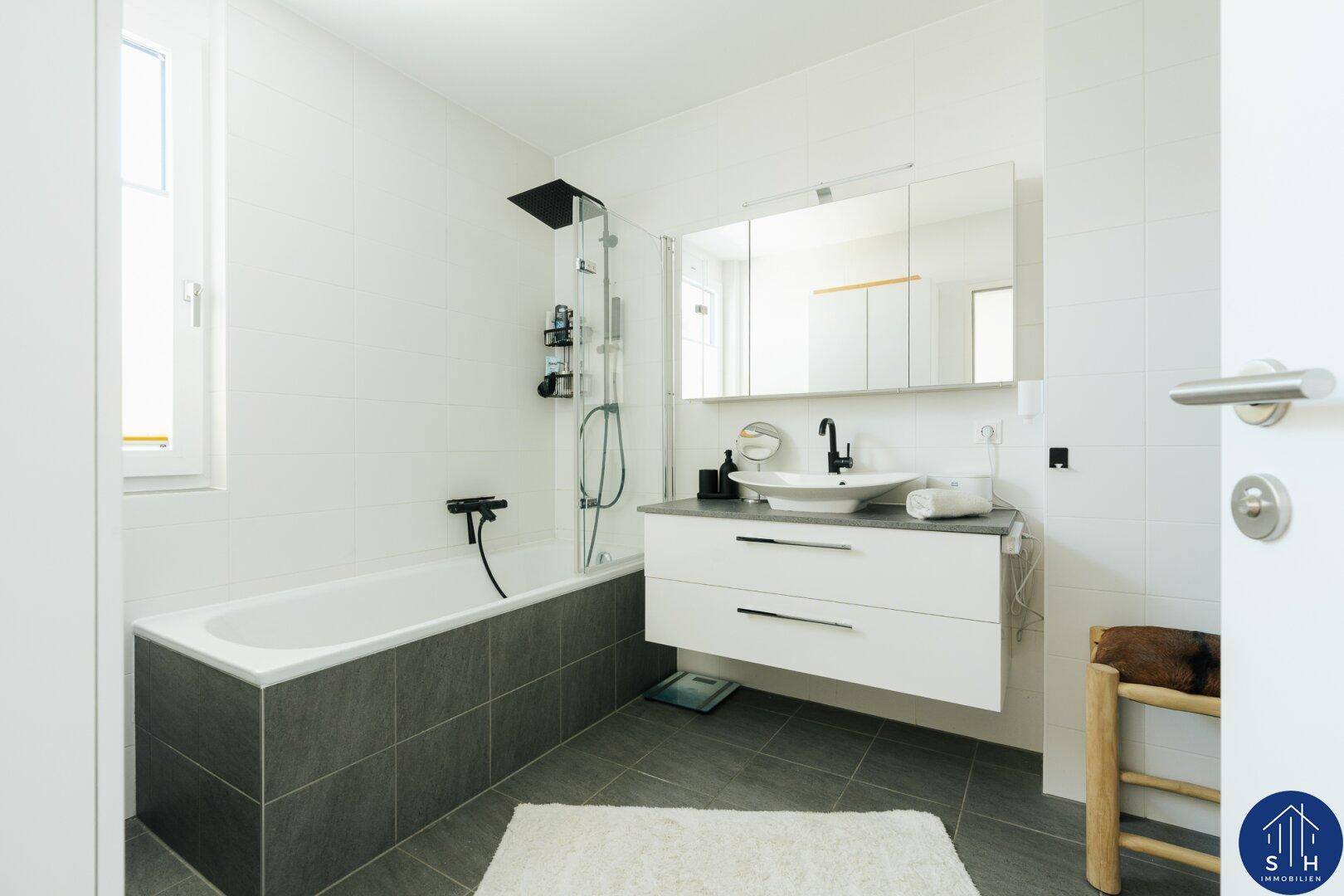 Modernes Badezimmer mit Badewanne, Dusche, schwebendem Waschtisch und Spiegelschrank in Weiß und Grau.