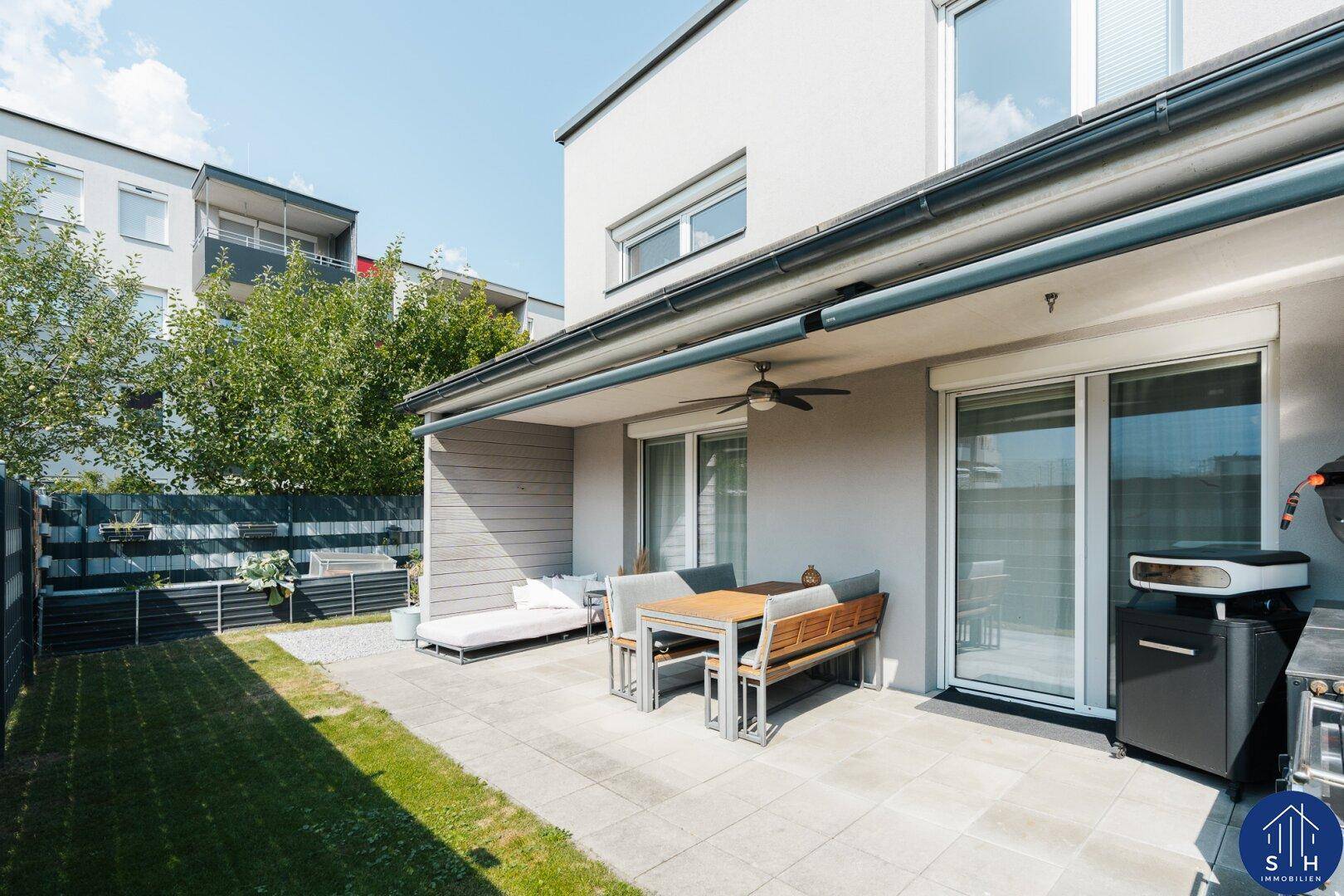 Geräumige Terrasse mit Essbereich, Grill und angrenzendem Rasen für entspannte Stunden im Freien.