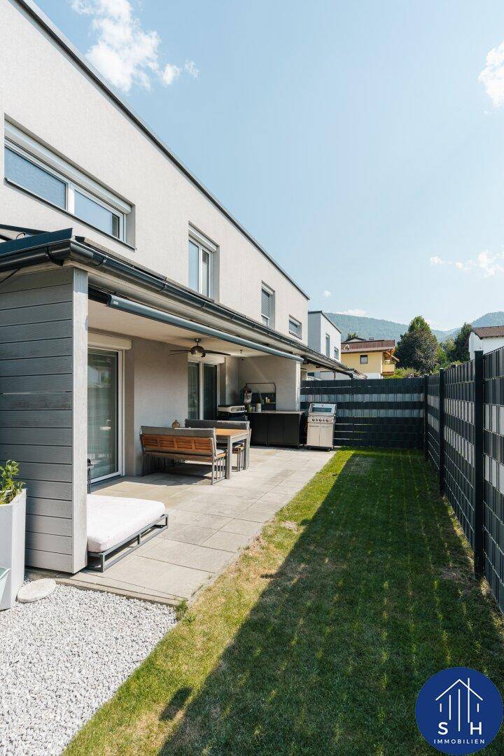 Geräumige Terrasse mit Essbereich im Freien, Grill und angrenzendem Rasen.
